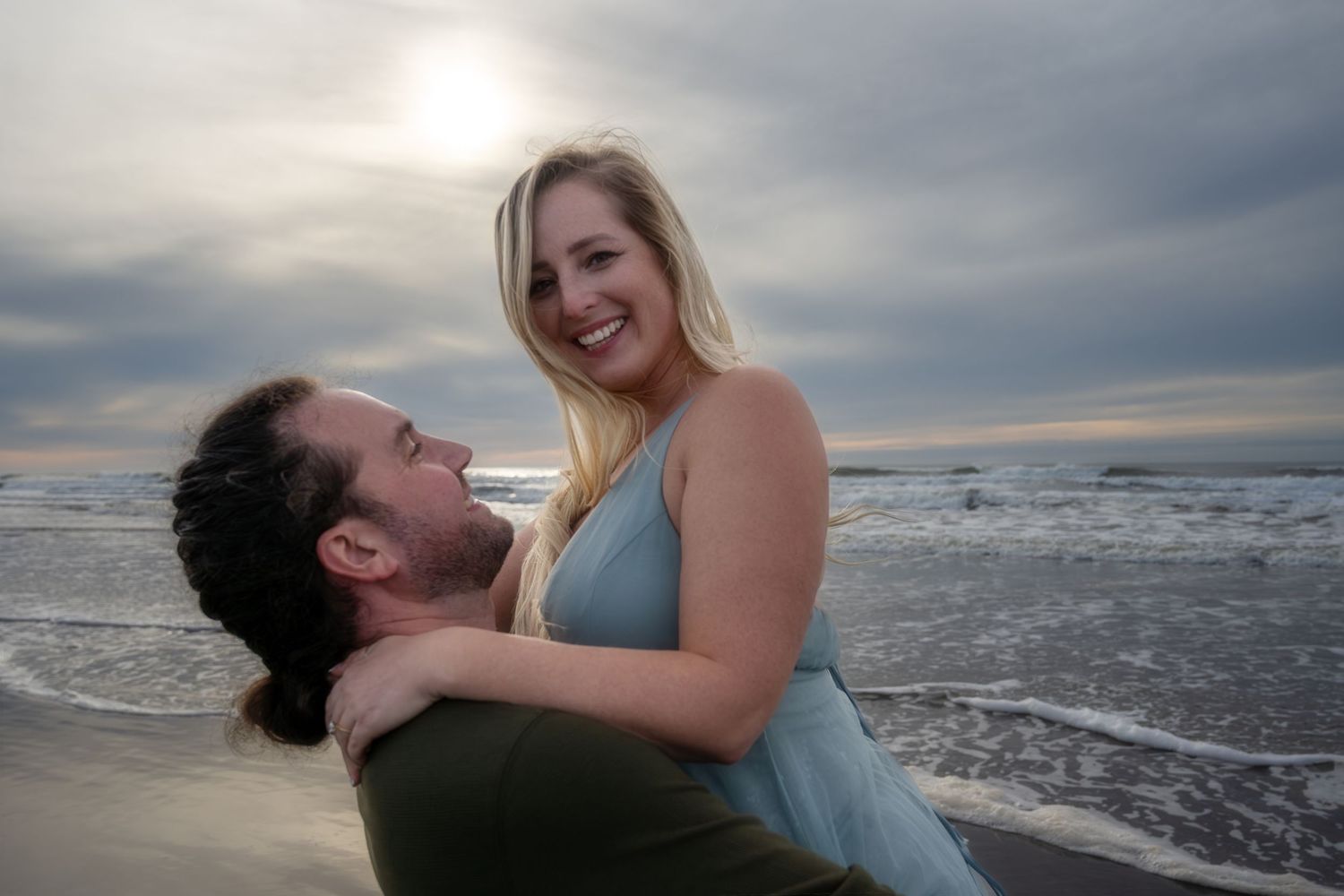 Romantic couple photos at sunset on a beach with dramatic cloudy sky.
