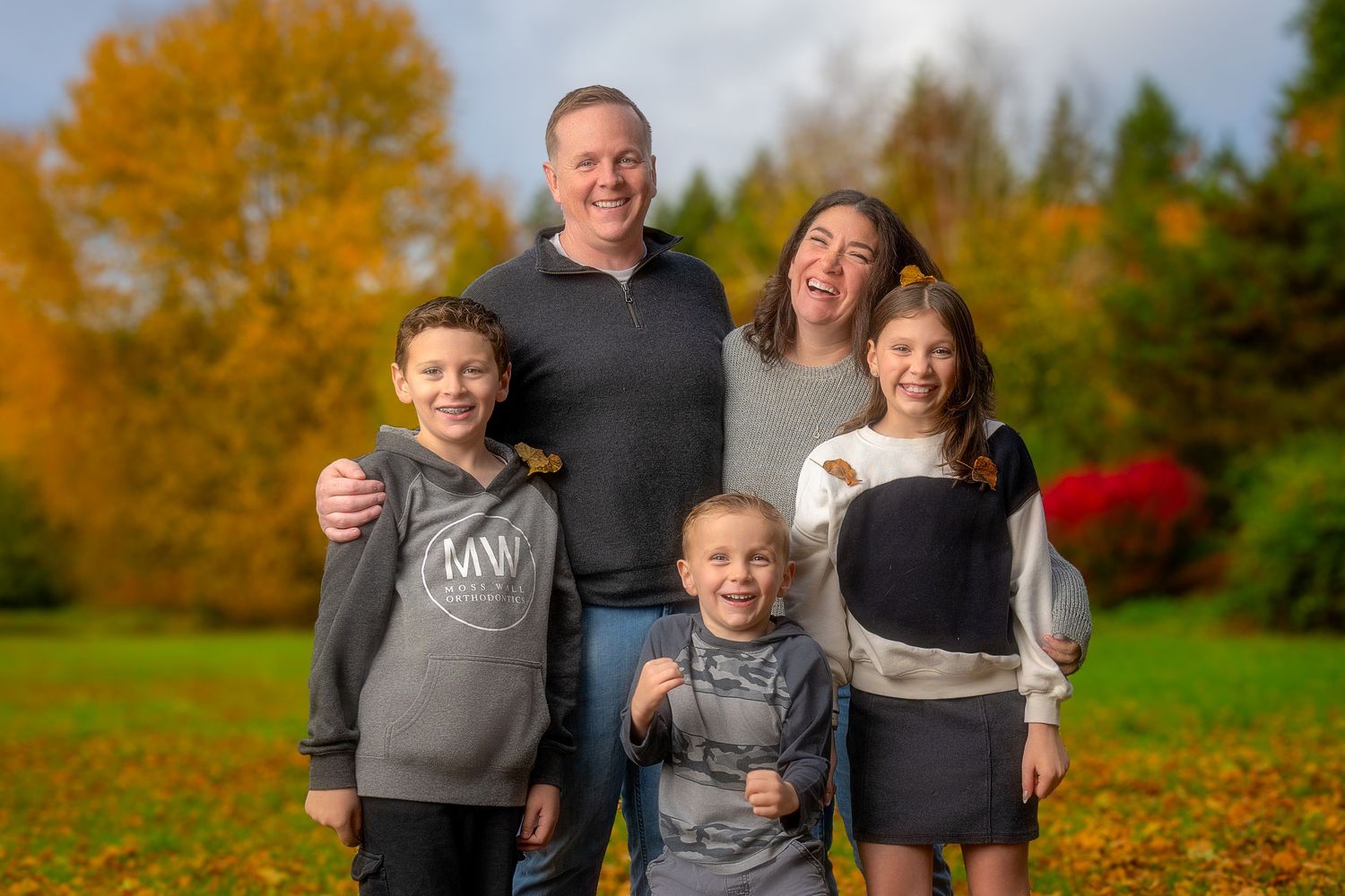Happy family enjoying autumn outdoors with colorful fall foliage in the background.