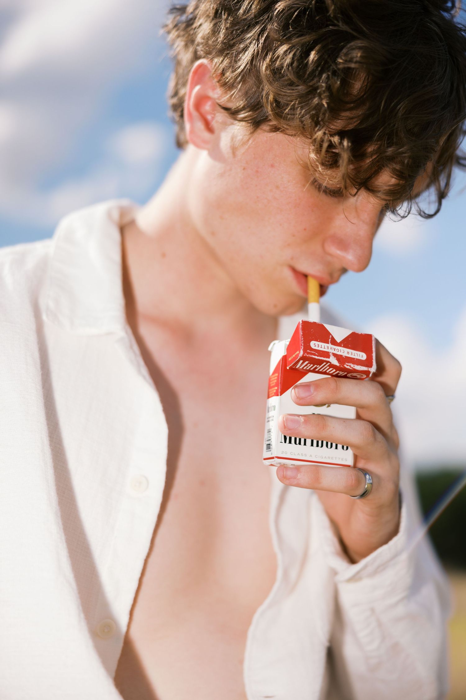 Close-up shot showing interaction with red cigarette pack in outdoor setting.