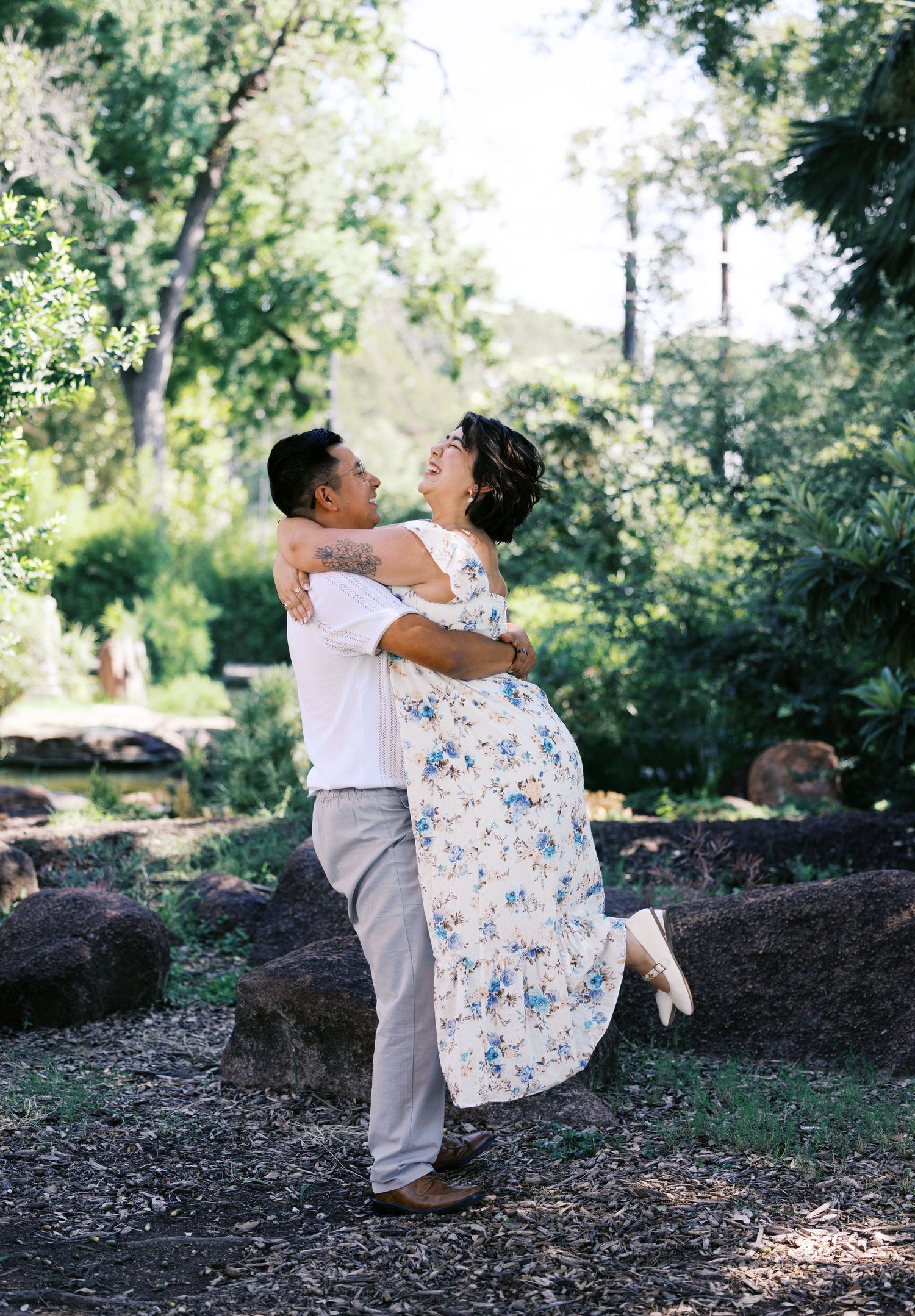 A playful moment between a couple as they dance in a sunlit garden setting.