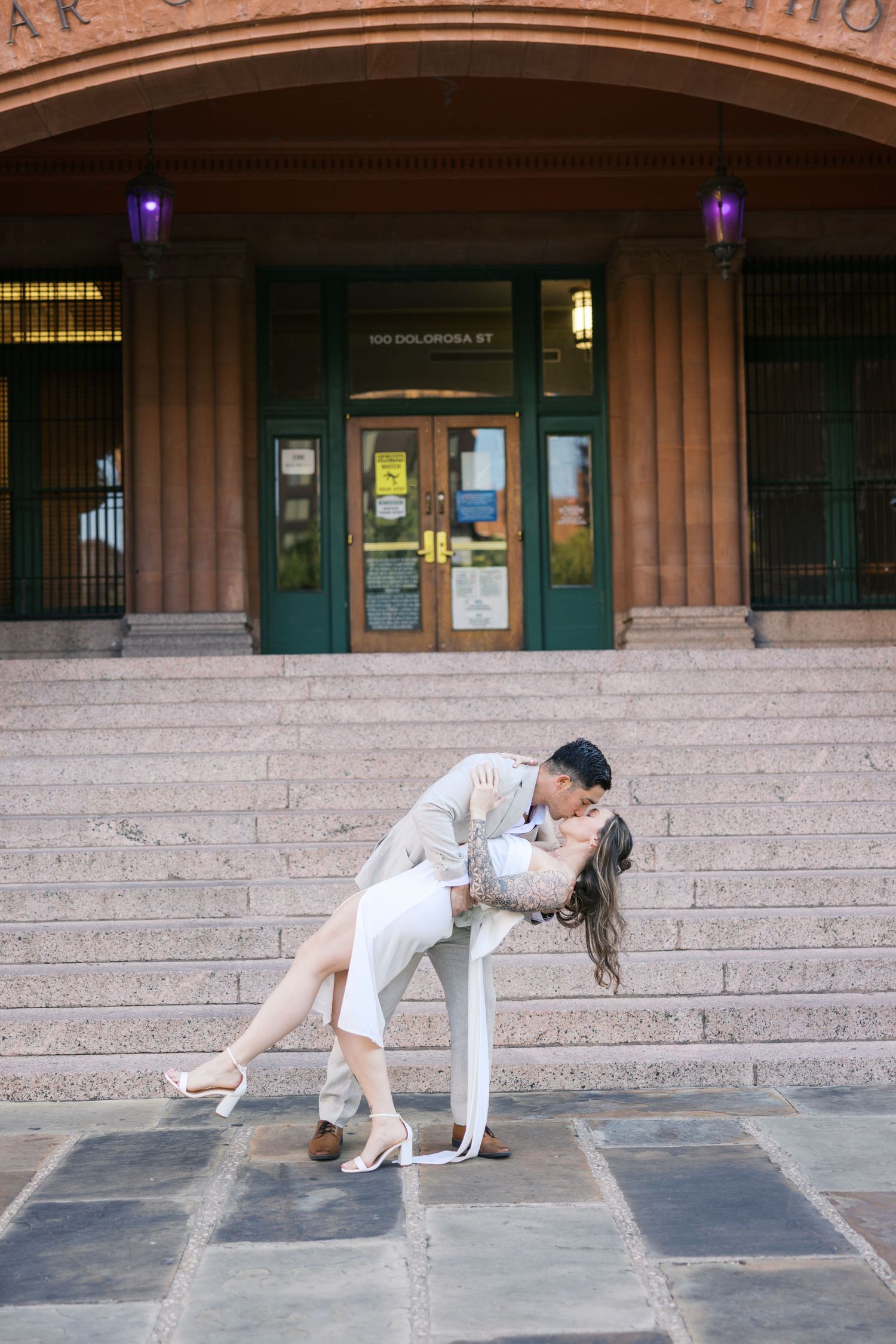 Dramatic dip pose sequence on courthouse steps during engagement photoshoot.
