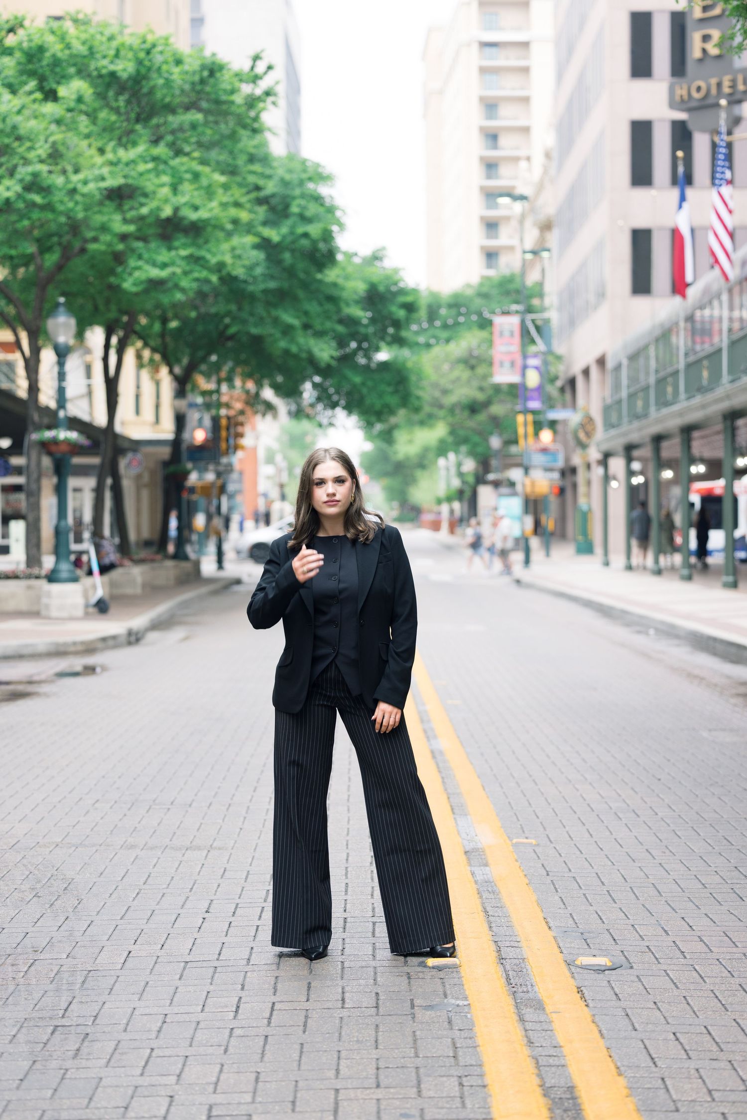 Street fashion photography on brick sidewalk with yellow road lines and urban scenery.