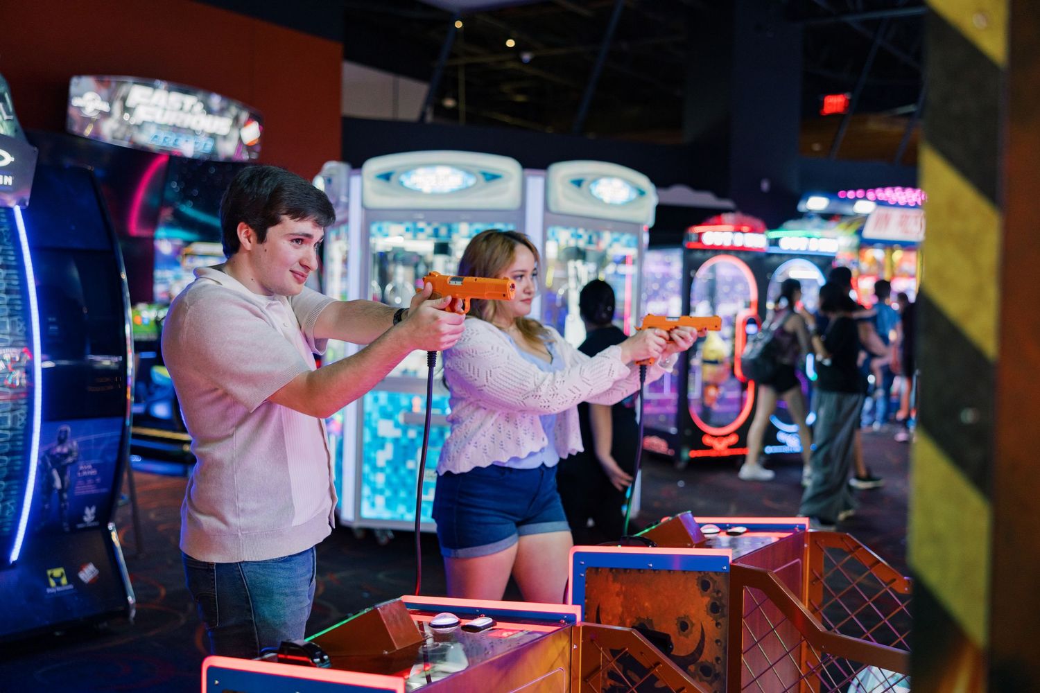 Gamers enjoying arcade machines in a dimly lit room with neon signage.