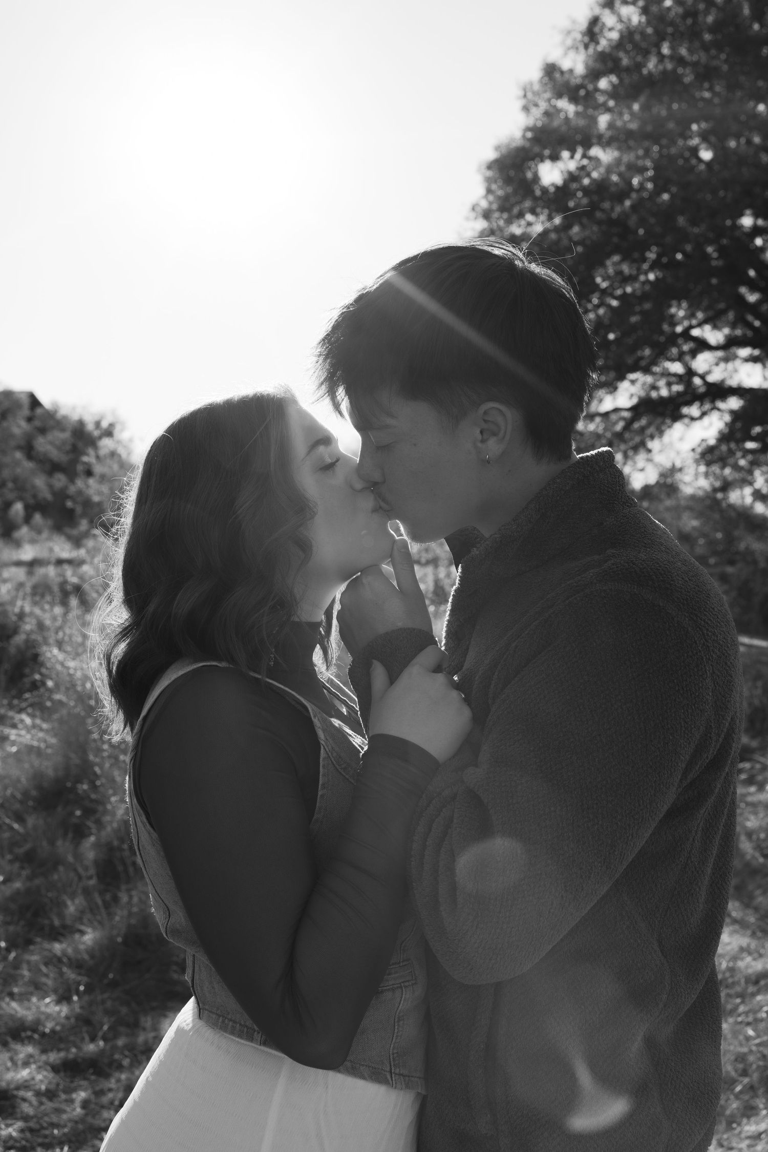 Romantic black and white portrait of a couple sharing an intimate moment in natural lighting.