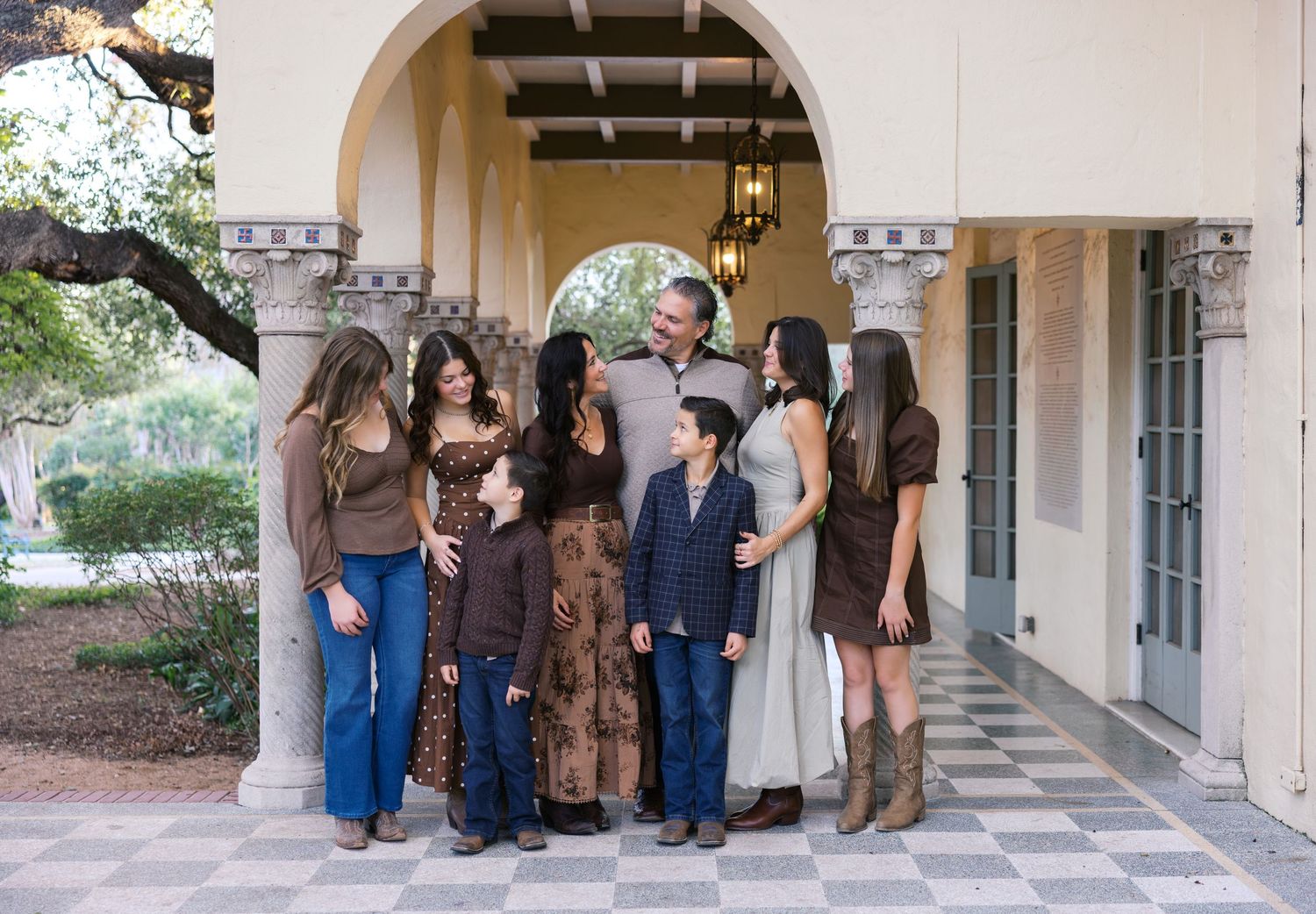 Group of friends gathered under an ornate archway in casual western-inspired outfits.