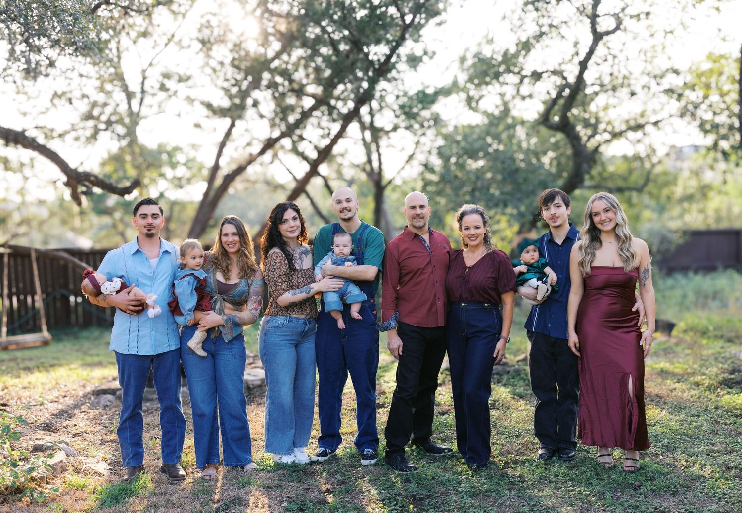 A large group poses together outdoors at sunset among trees.