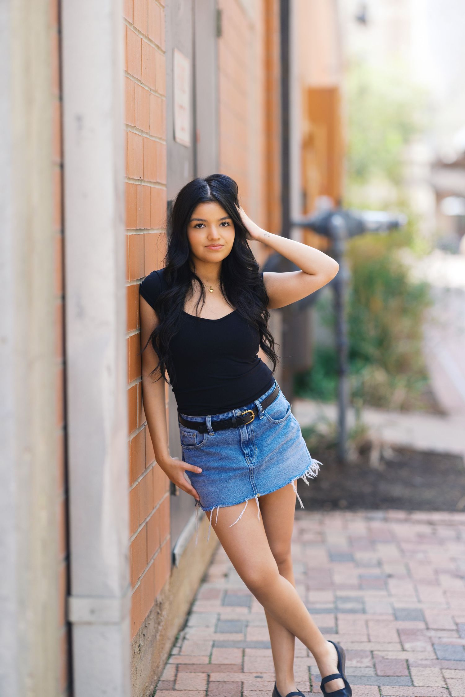 Stylish casual portraits captured against a warm-toned stucco wall and brick pathway.