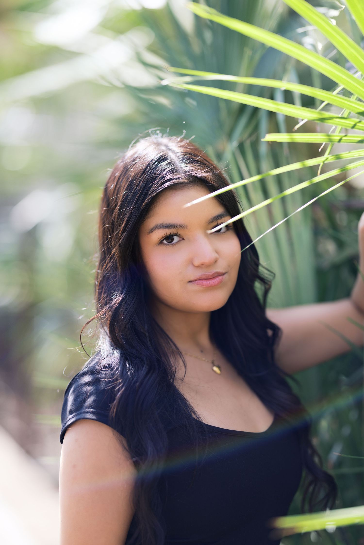 Portrait shot against tropical foliage background with black top and natural lighting.