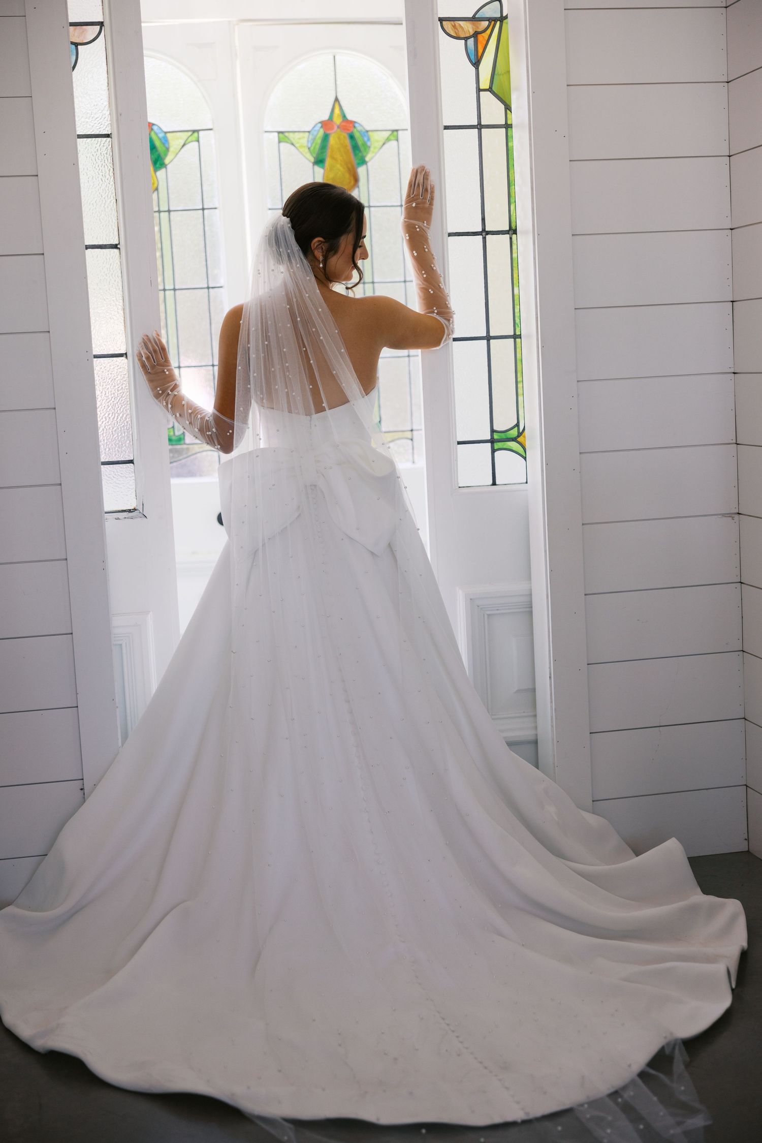 Series showing flowing train of white wedding dress in sunlit chapel interior.