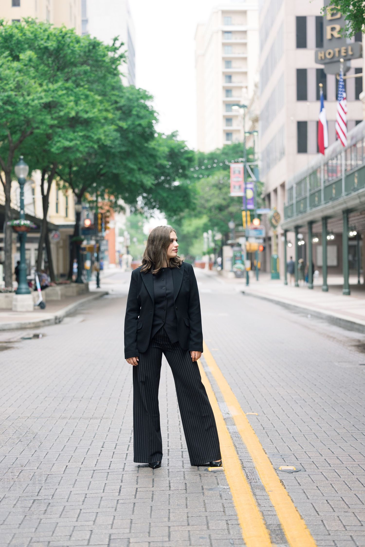 Urban fashion shoot on city street with yellow lines and green trees.