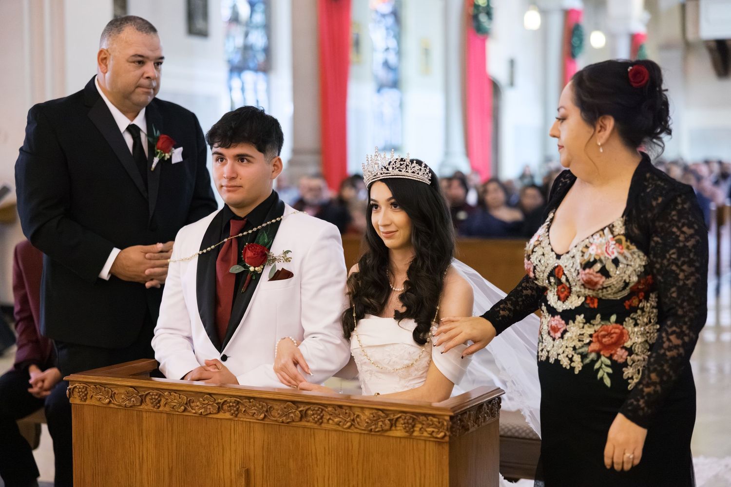 Wedding ceremony taking place at an ornate church altar with decorative red banners.