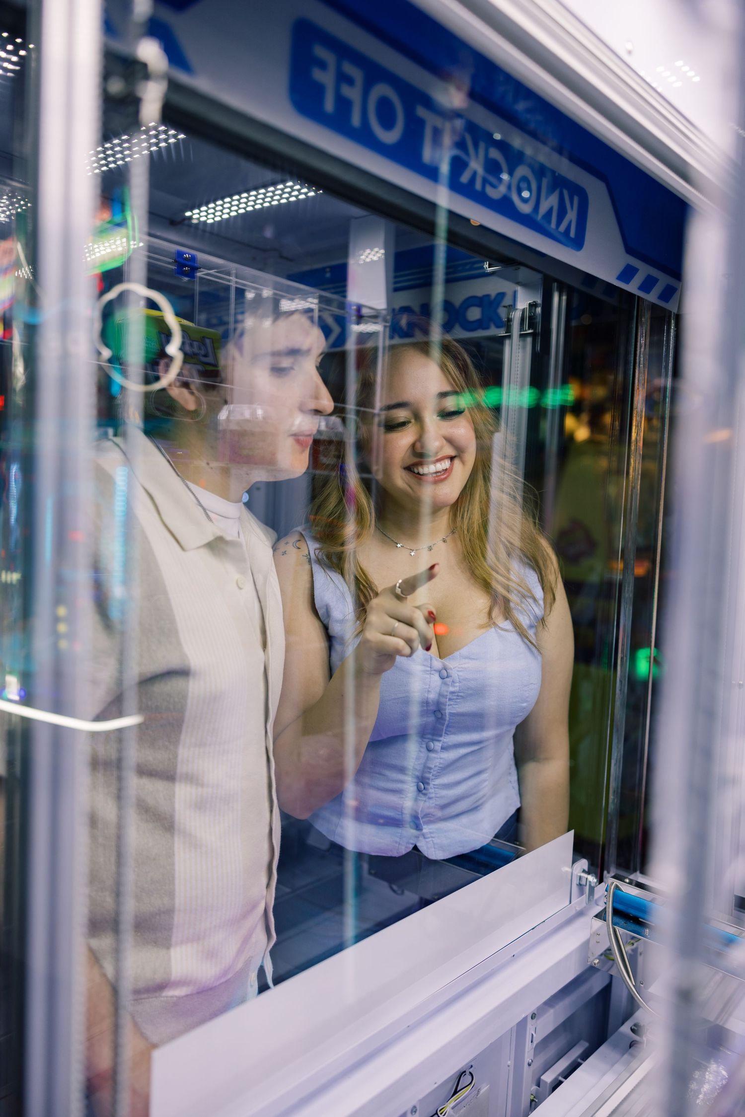 Multiple reflections in glass windows showing people at an arcade or entertainment venue.