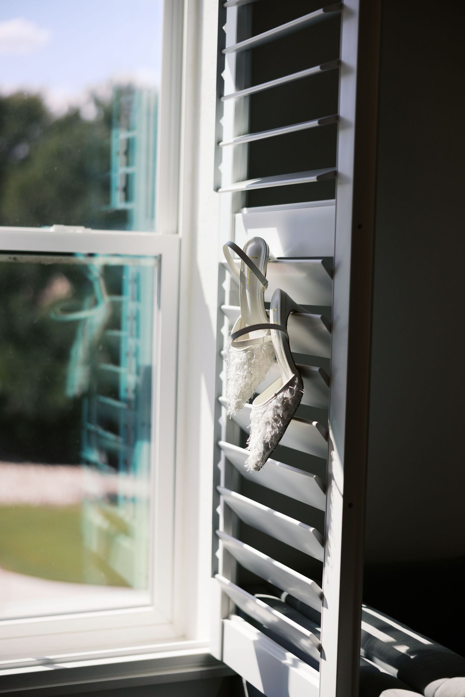 Close-up view of white window shutters with sunlight streaming through.