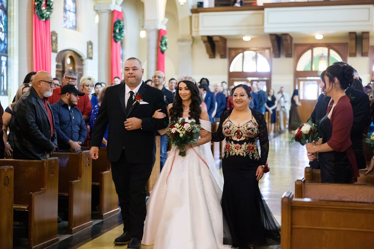 A traditional Catholic church wedding ceremony with attendees walking down the center aisle.