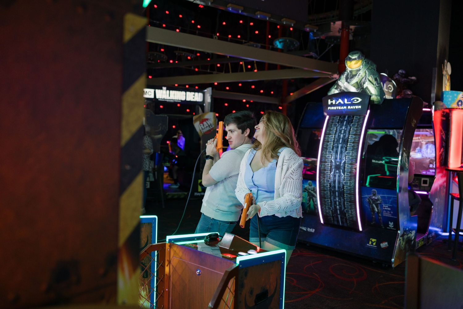 Couple enjoying a night out at an arcade with colorful neon lights in the background.