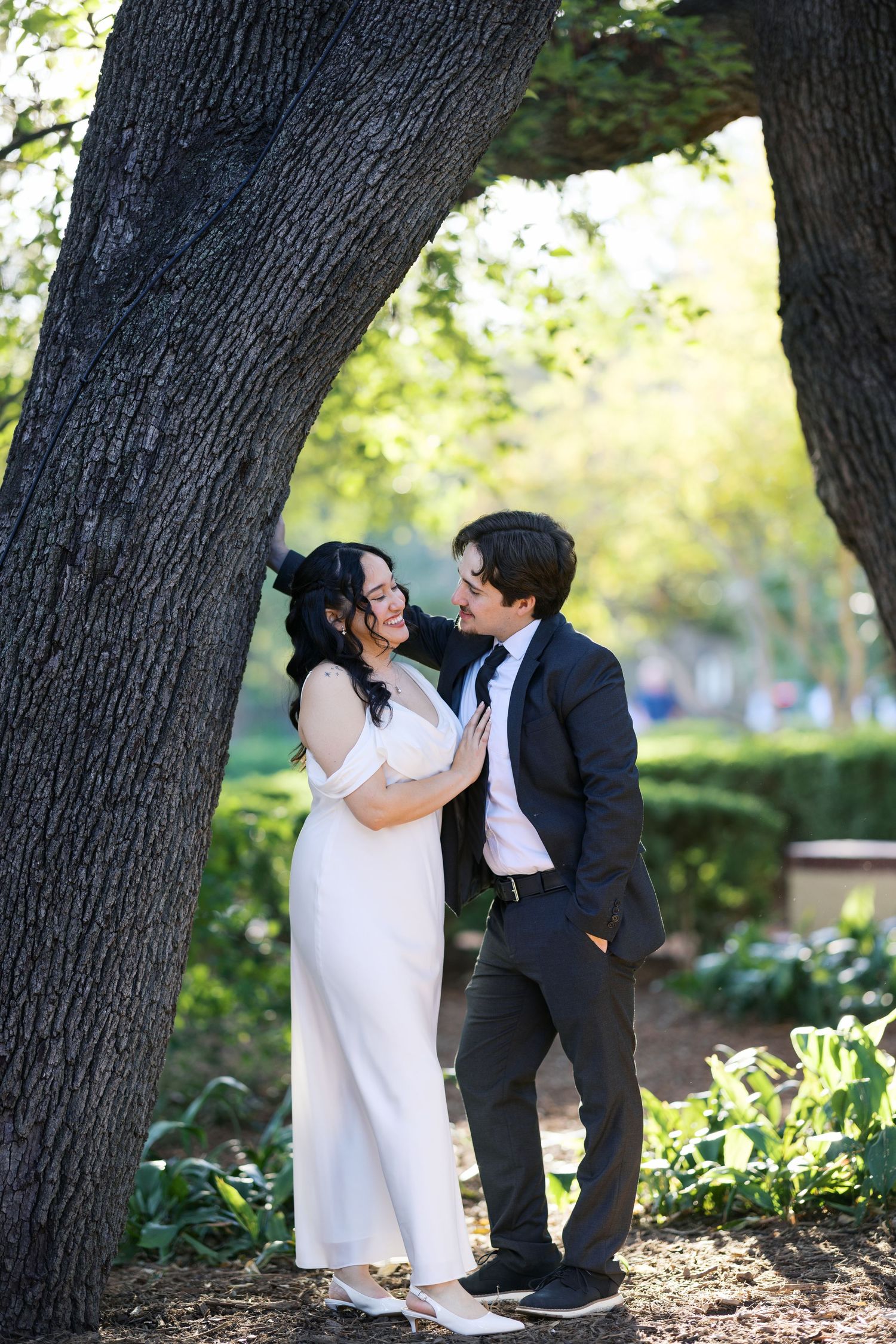 Romantic wedding portraits captured under large oak trees in a garden setting.