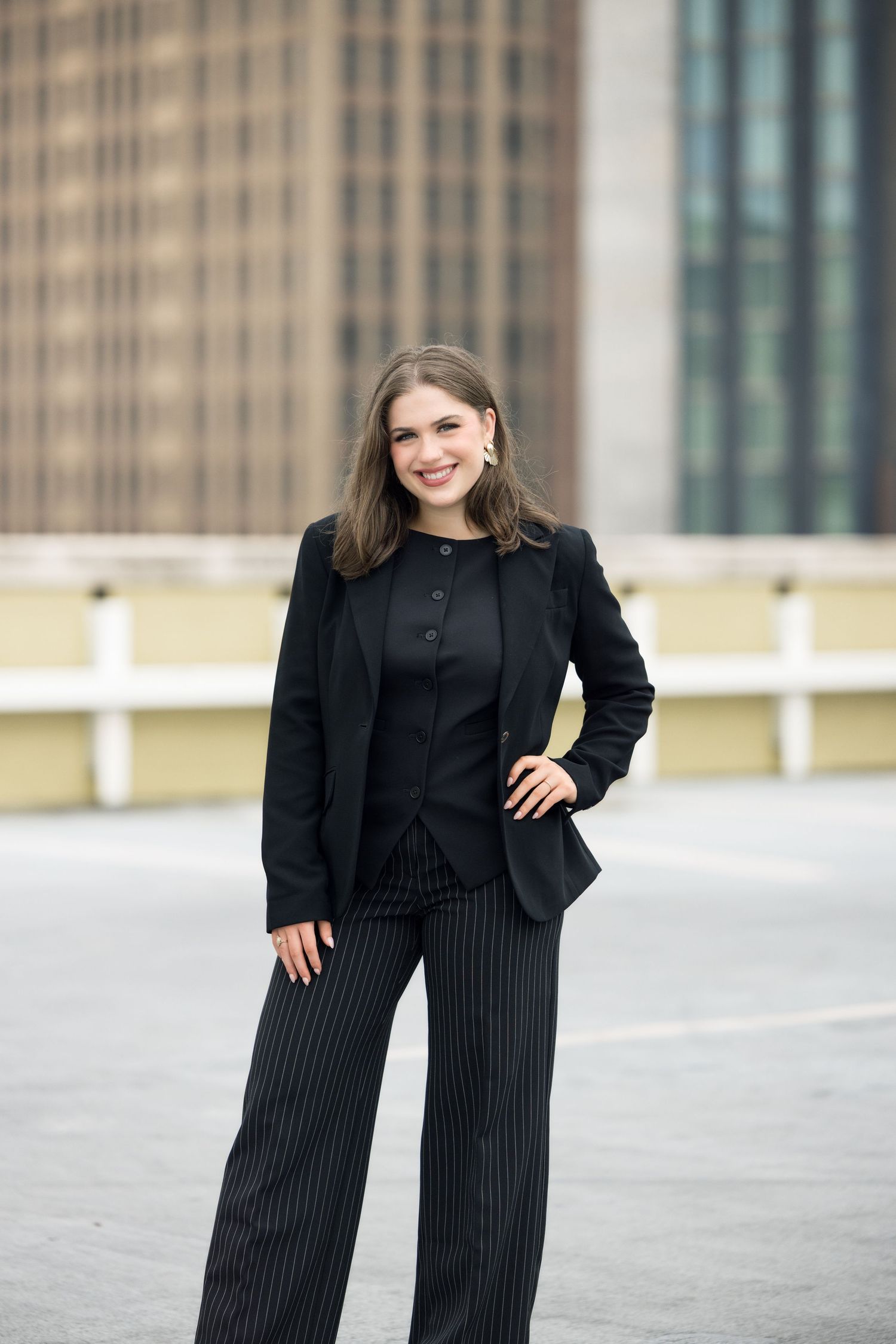 Fashion portrait against urban architecture featuring a black blazer and pinstripe pants.