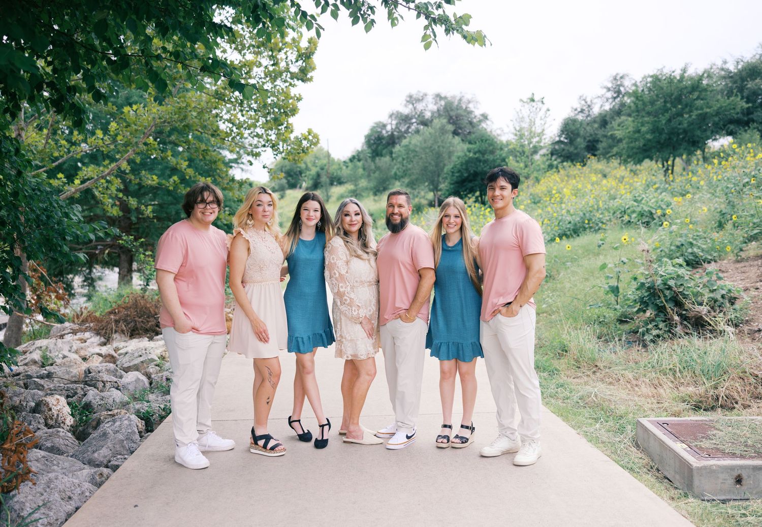 Group walking together in coordinated pastel and white outfits along a stone path outdoors.