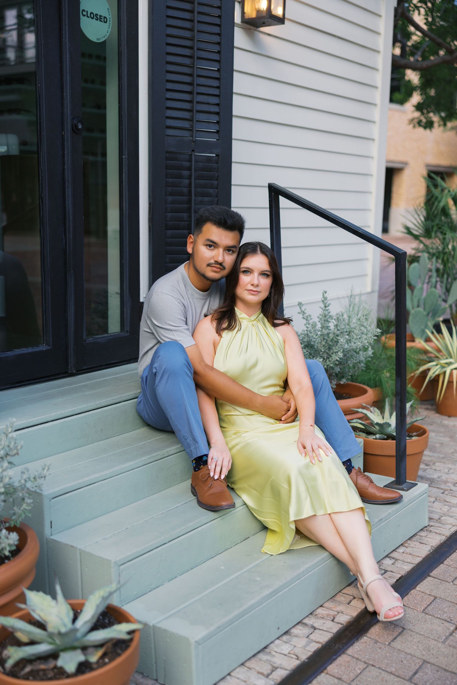 Couple relaxing on white porch steps during outdoor photoshoot.
