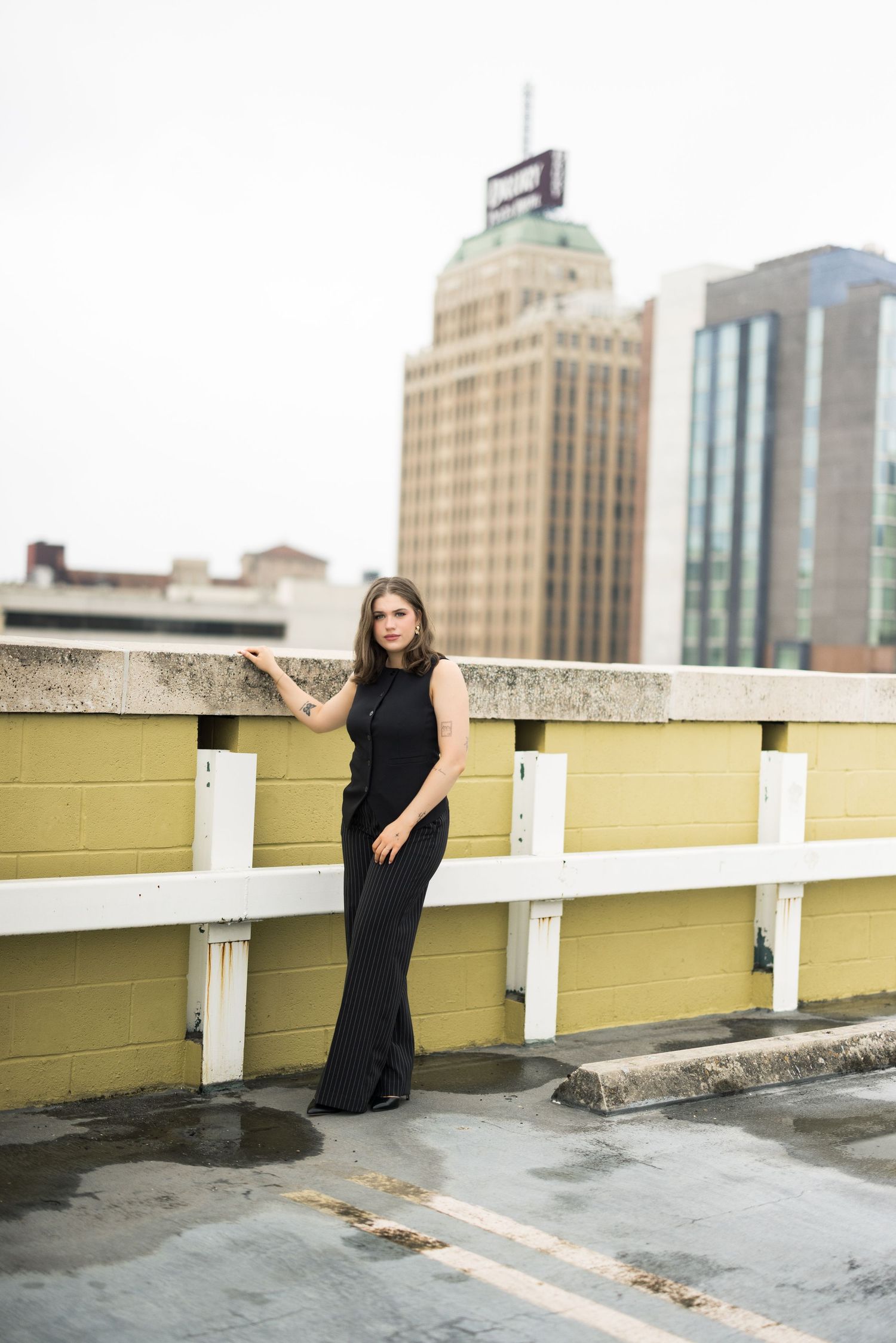 Urban rooftop fashion shoot featuring a black sleeveless outfit against downtown architecture.