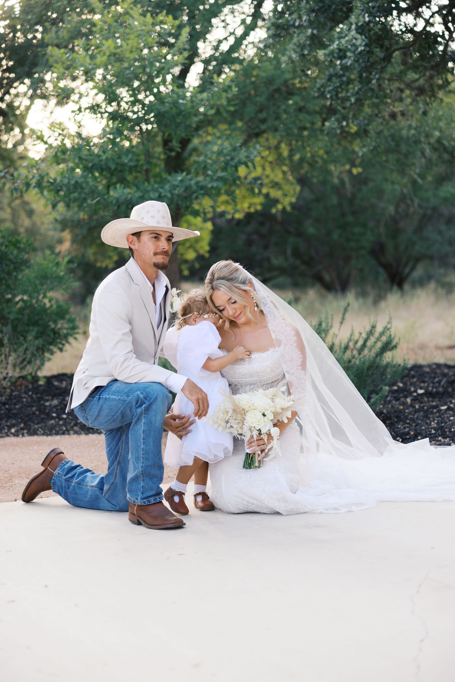 Romantic wedding portraits on white backdrop with cowboy boots and flowing bridal veil.
