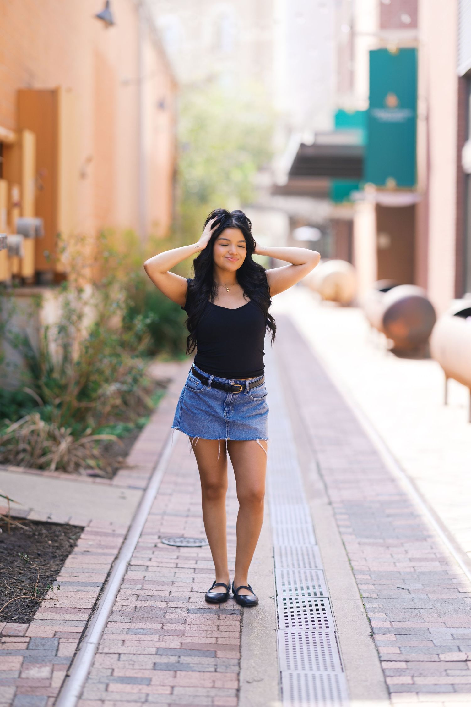 A playful portrait session along a brick-paved walkway with teal accents and planters.