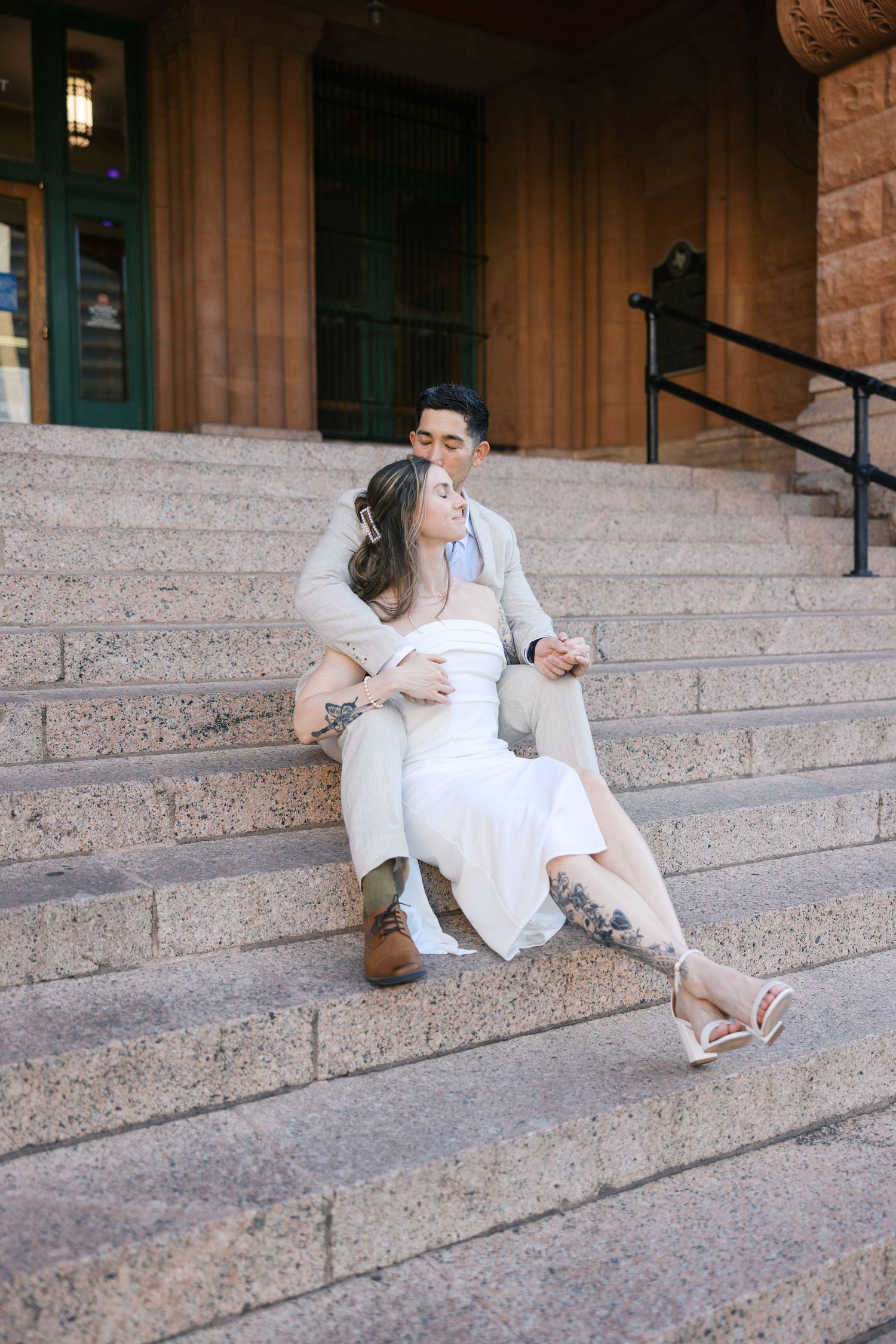 Couple sharing romantic moments on grand courthouse steps.