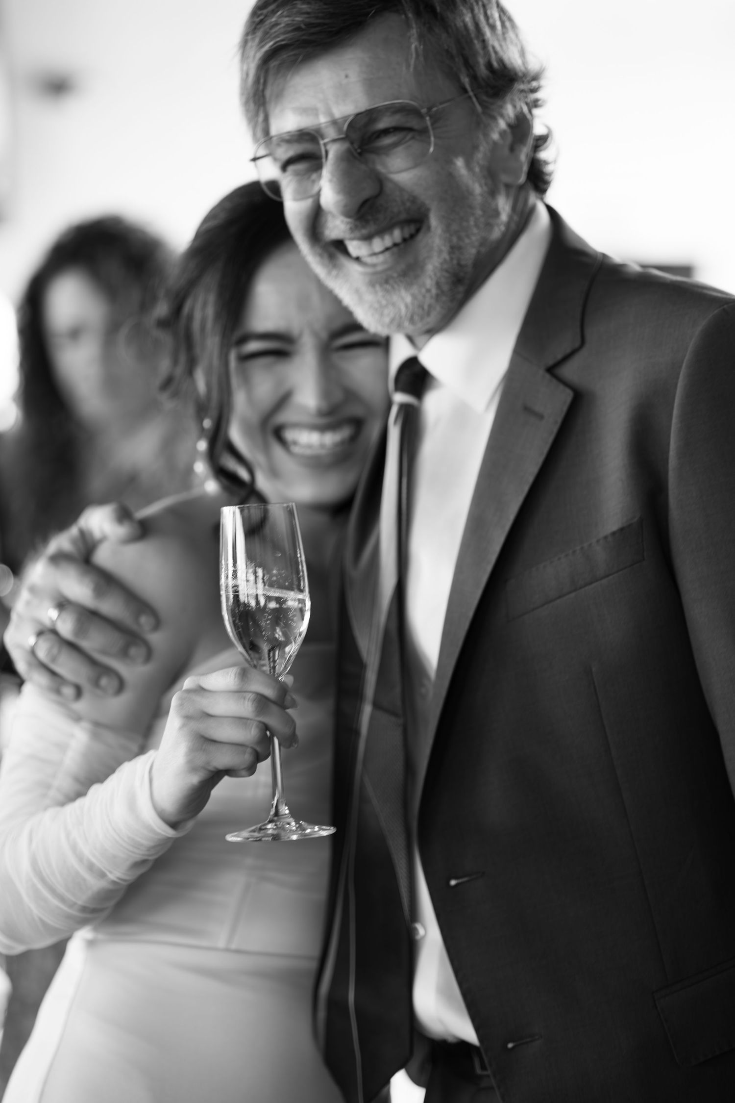 Black and white candid shots of joyful laughter during wedding toasts.