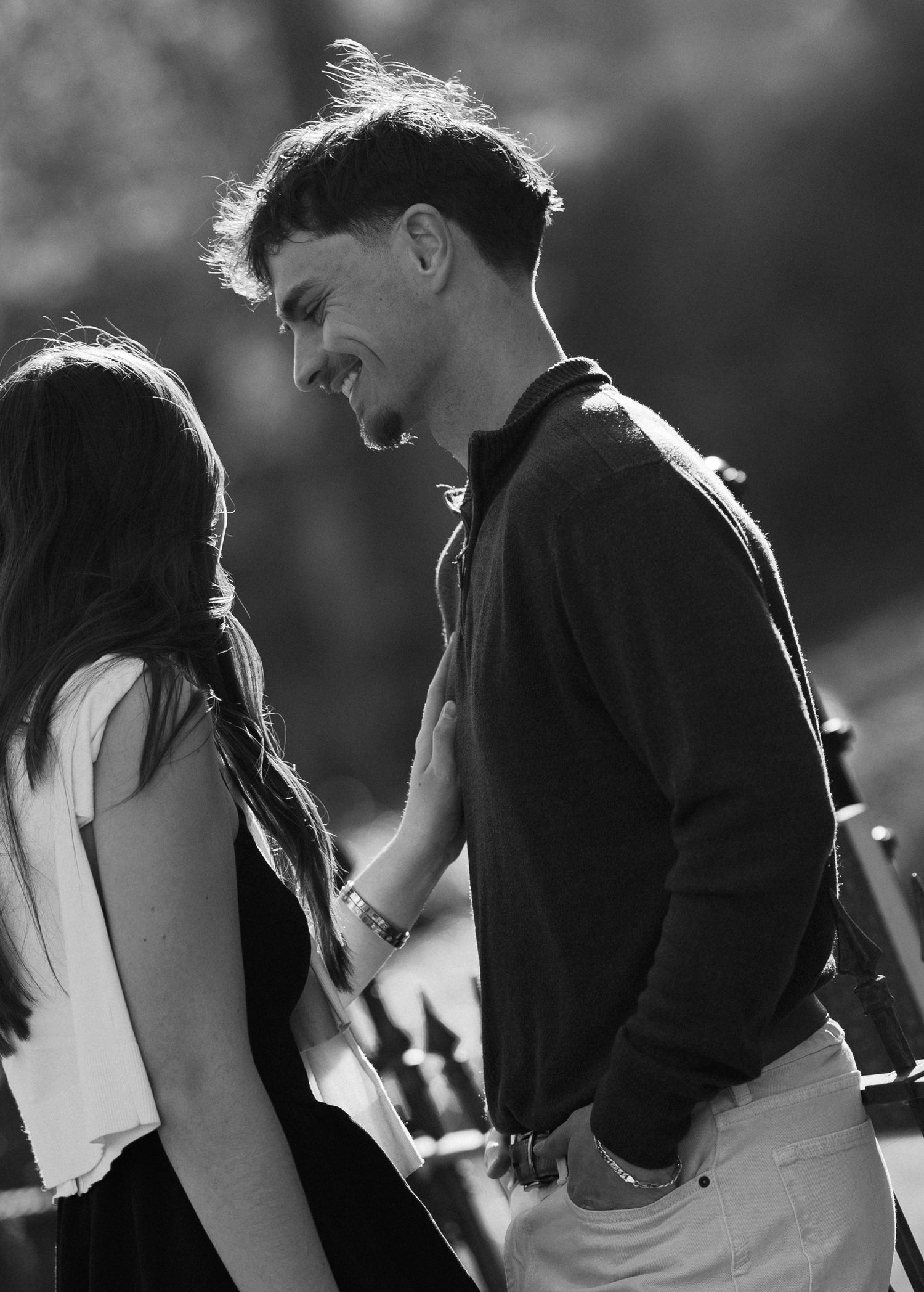 Black and white photo of a young couple sharing a romantic moment outdoors, man smiling down at woman.