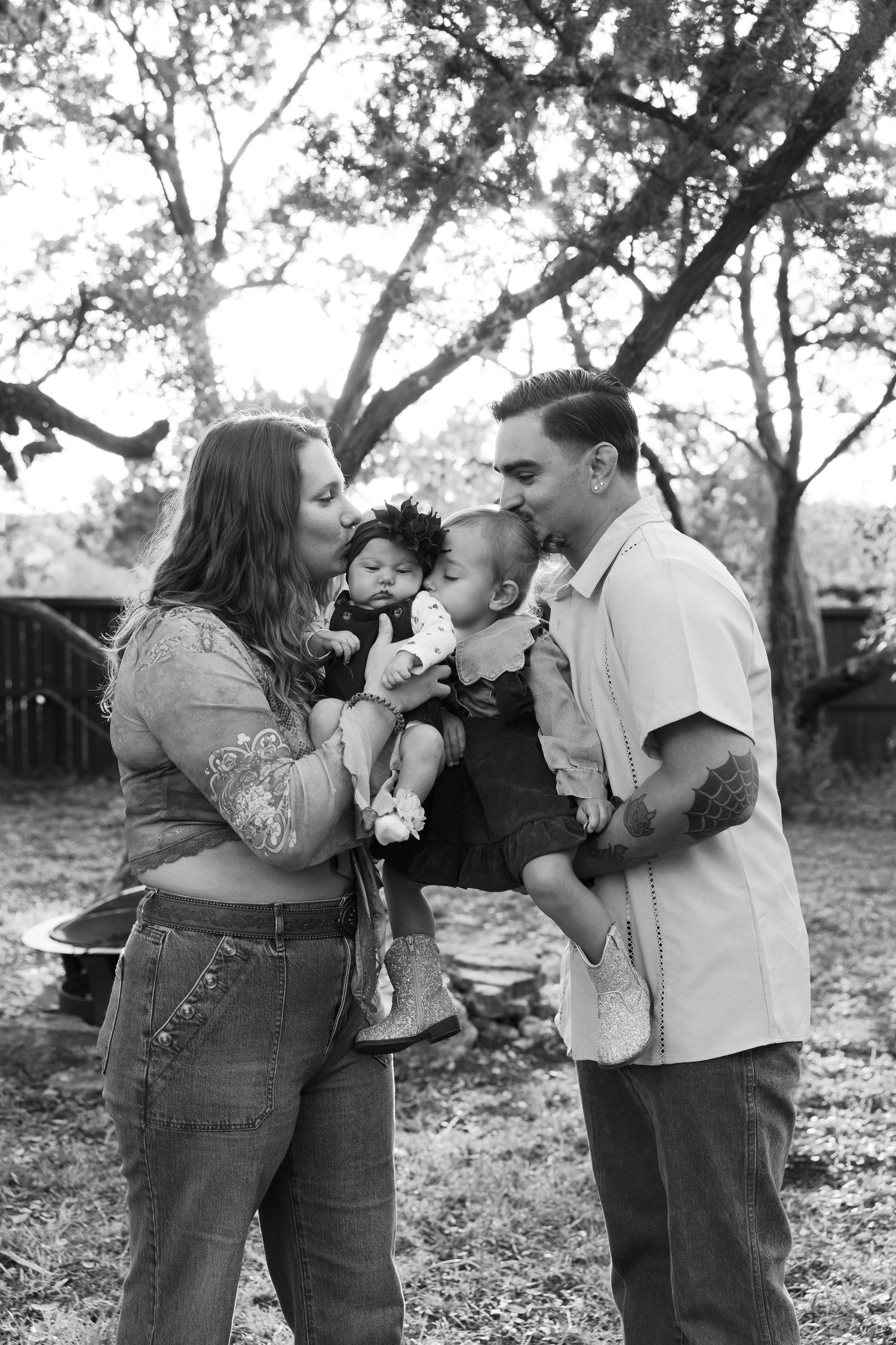A tender family moment captured in black and white under tree branches.
