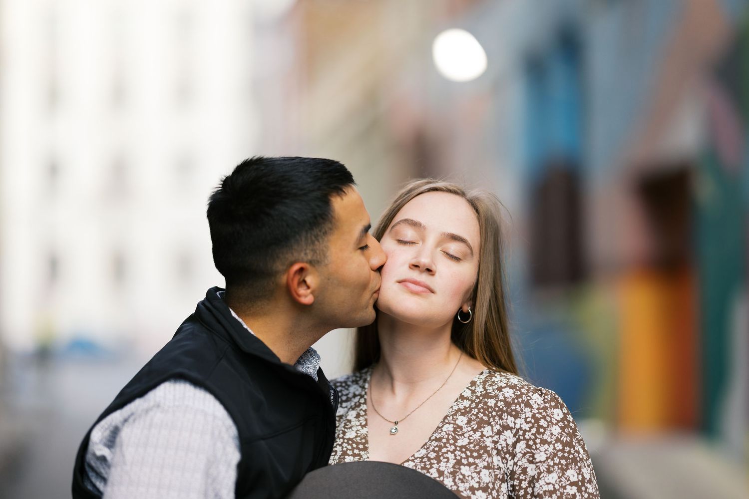 A romantic moment captured against a vibrant wall mural background.