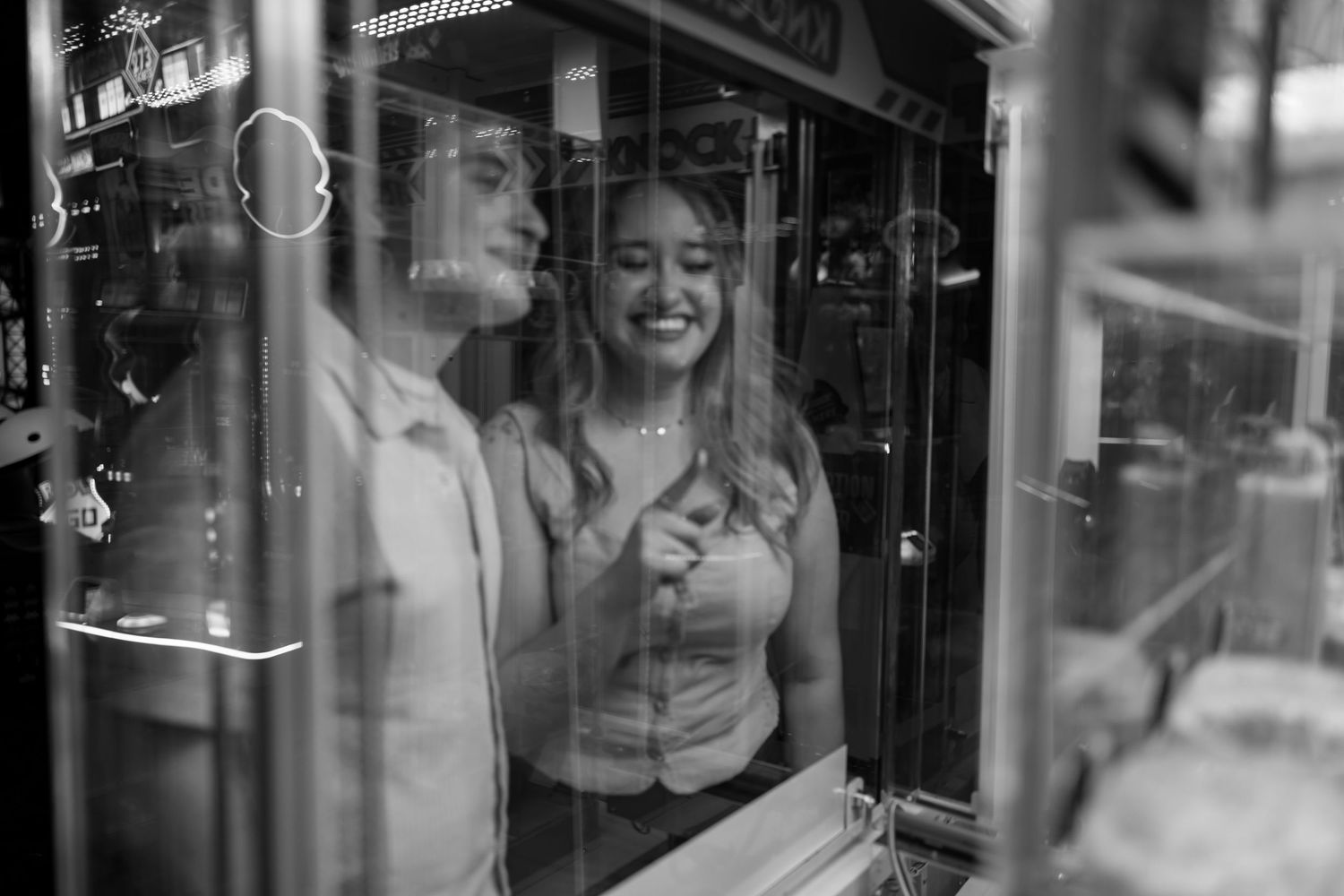 Black and white reflection of people through glass at an entertainment venue.