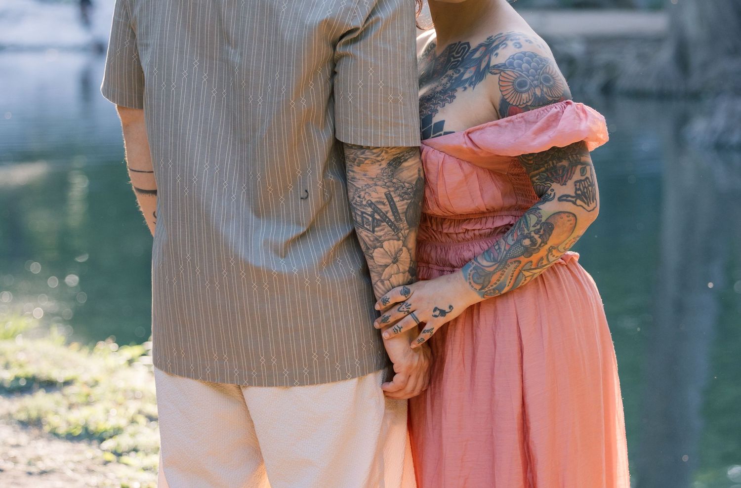 A couple shares an intimate moment by the water's edge during sunset.