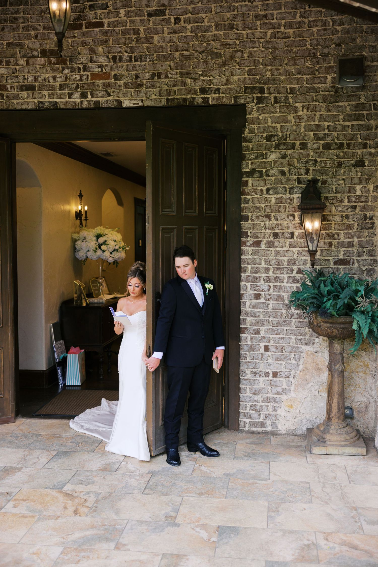 Bride and groom share first look moment at rustic brick venue doorway.