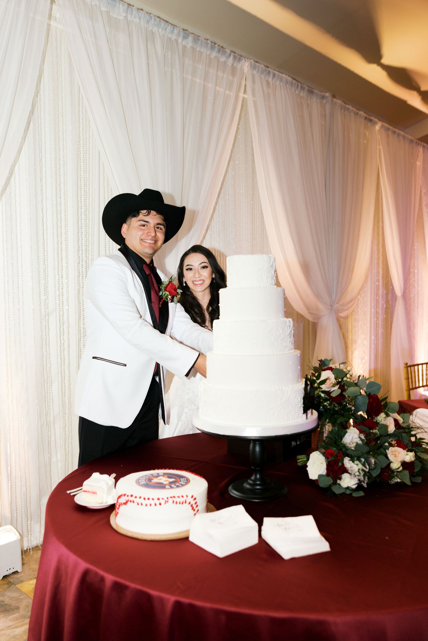 Newlyweds cutting their elegant white wedding cake at the reception.