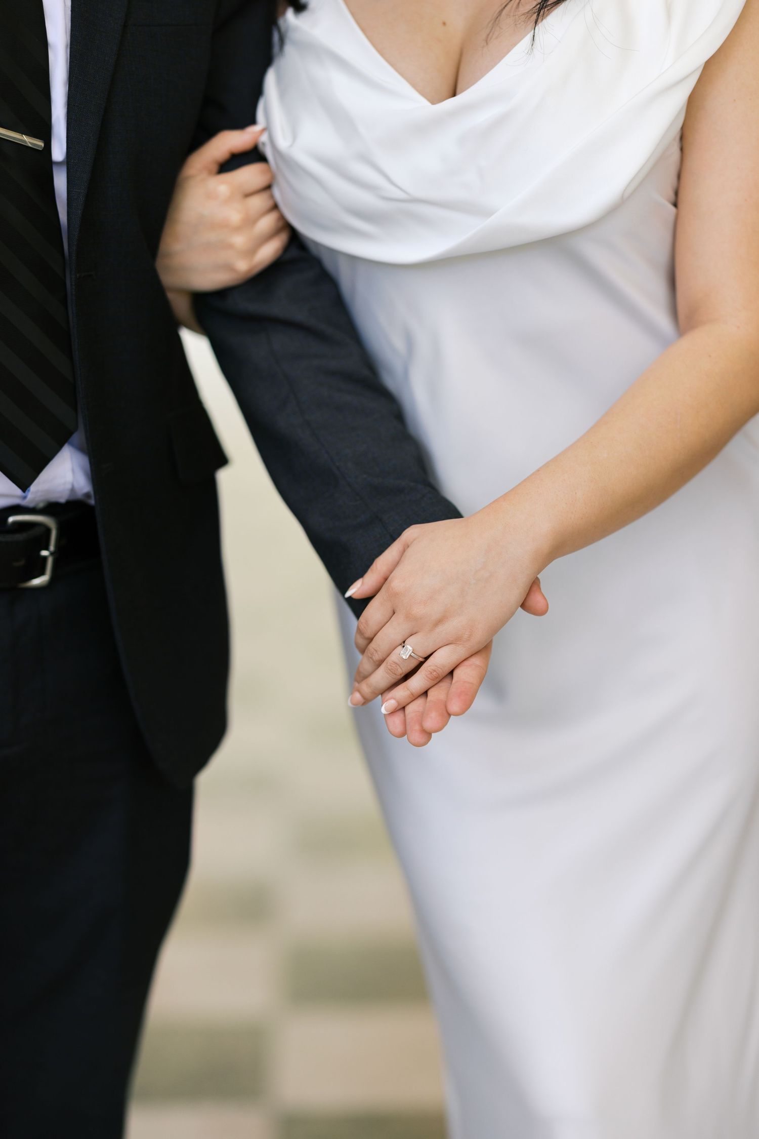 Close-up details of a white wedding dress against a black suit.