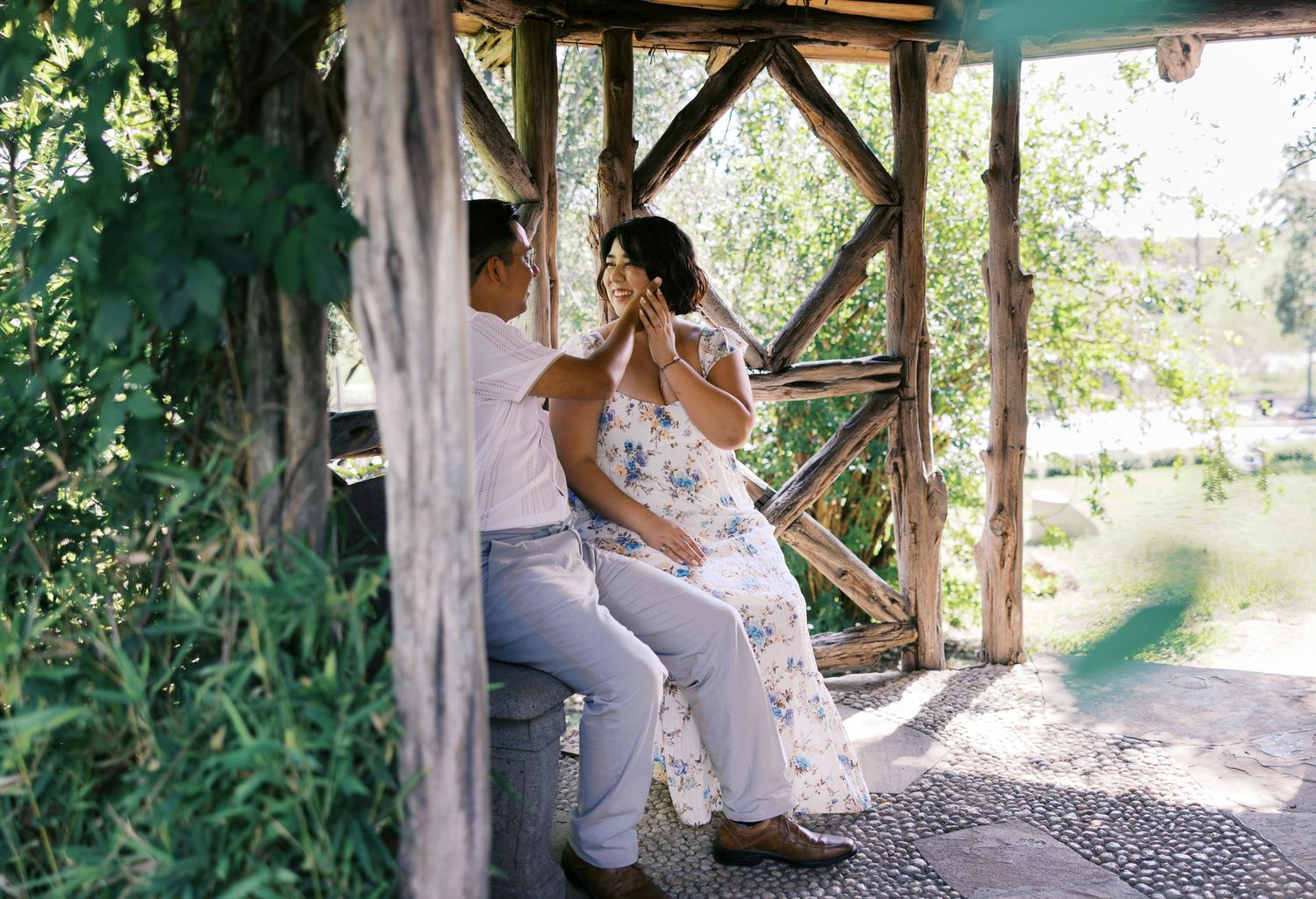 A romantic moment shared in a rustic wooden gazebo overlooking a garden pond.