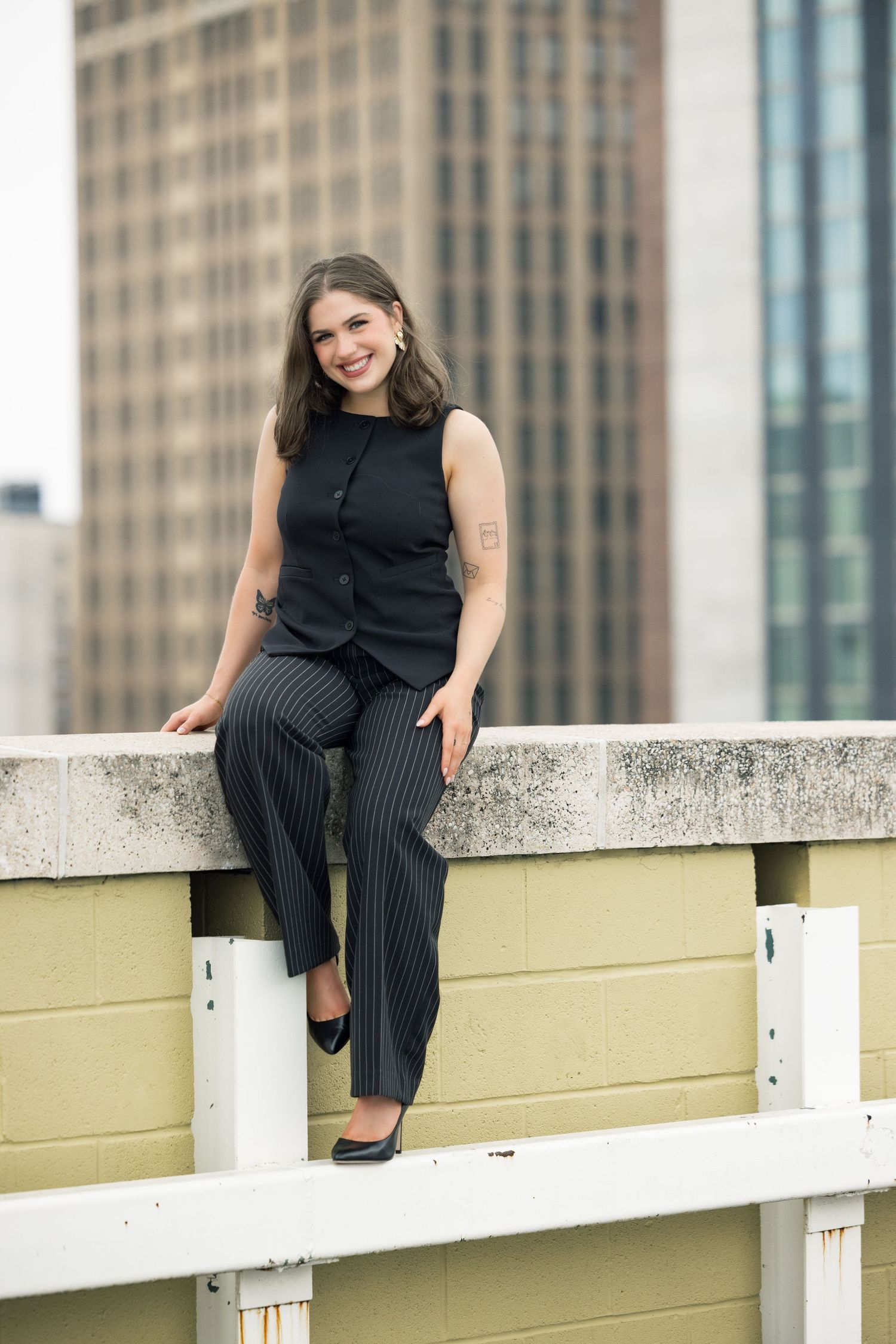 Rooftop fashion photography featuring pinstripe pants and sleeveless top against city skyline.