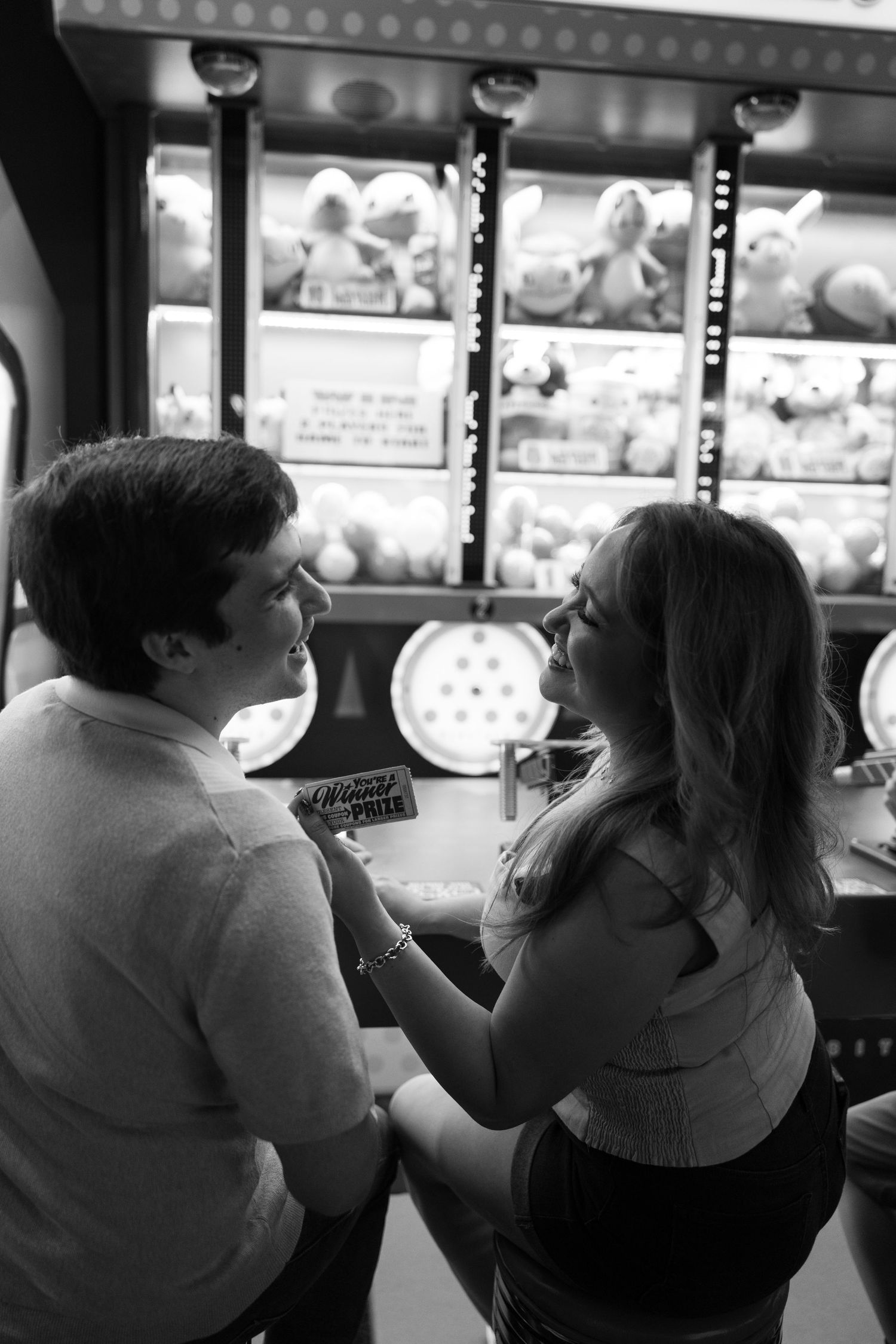 Black and white photo of people sitting at an arcade game counter.