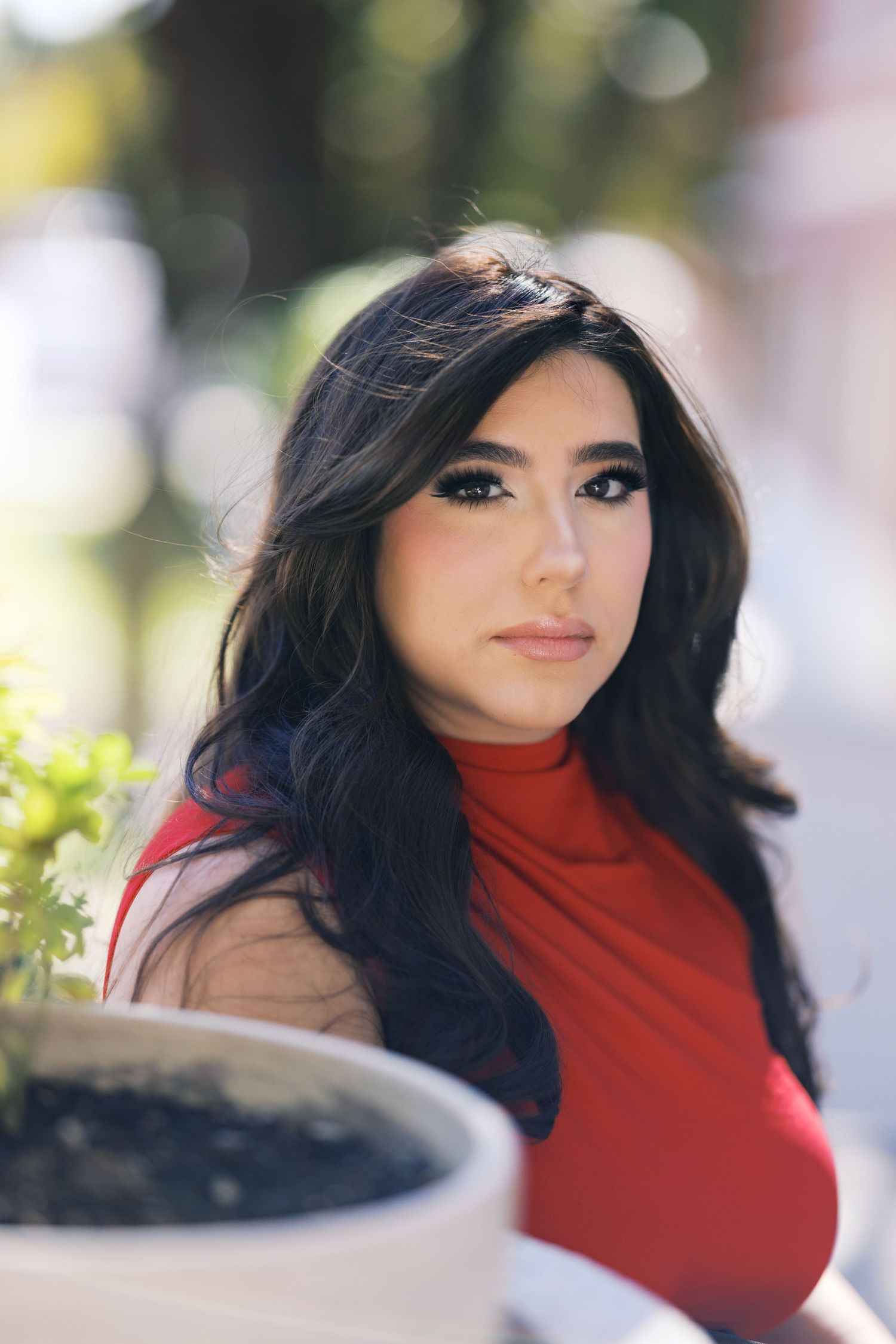 A close-up portrait featuring a red turtleneck and dramatic makeup.