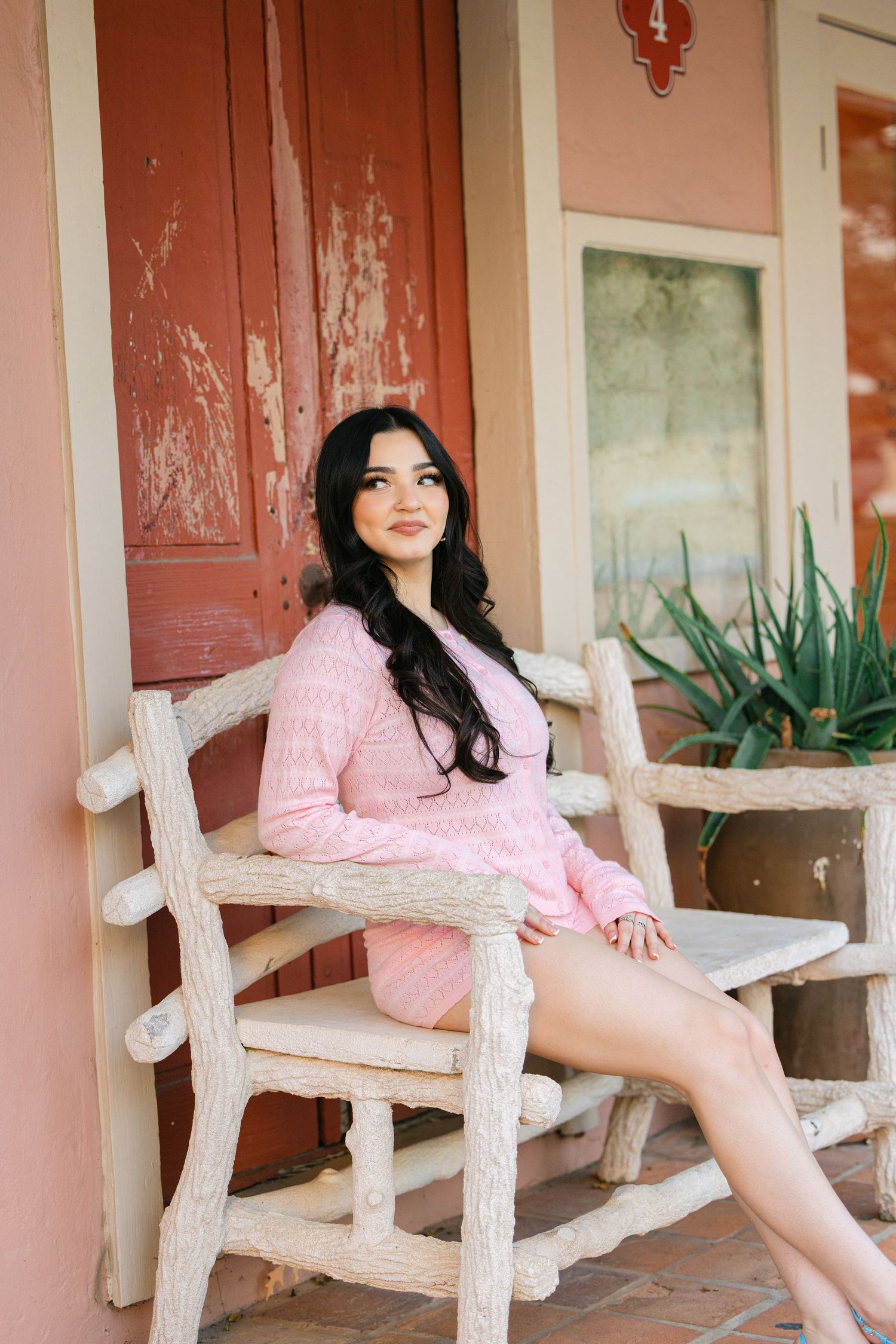 Someone relaxing on a rustic wooden porch chair in pink loungewear.