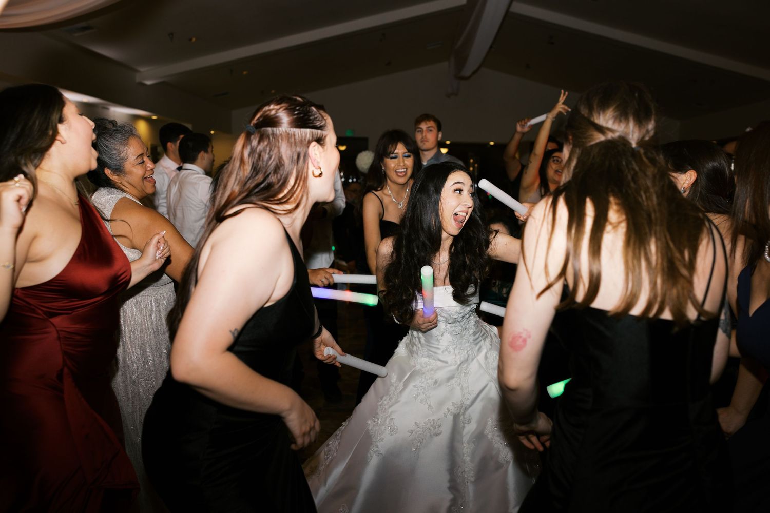 Party guests dancing and celebrating on a dimly lit dance floor at a lively event.