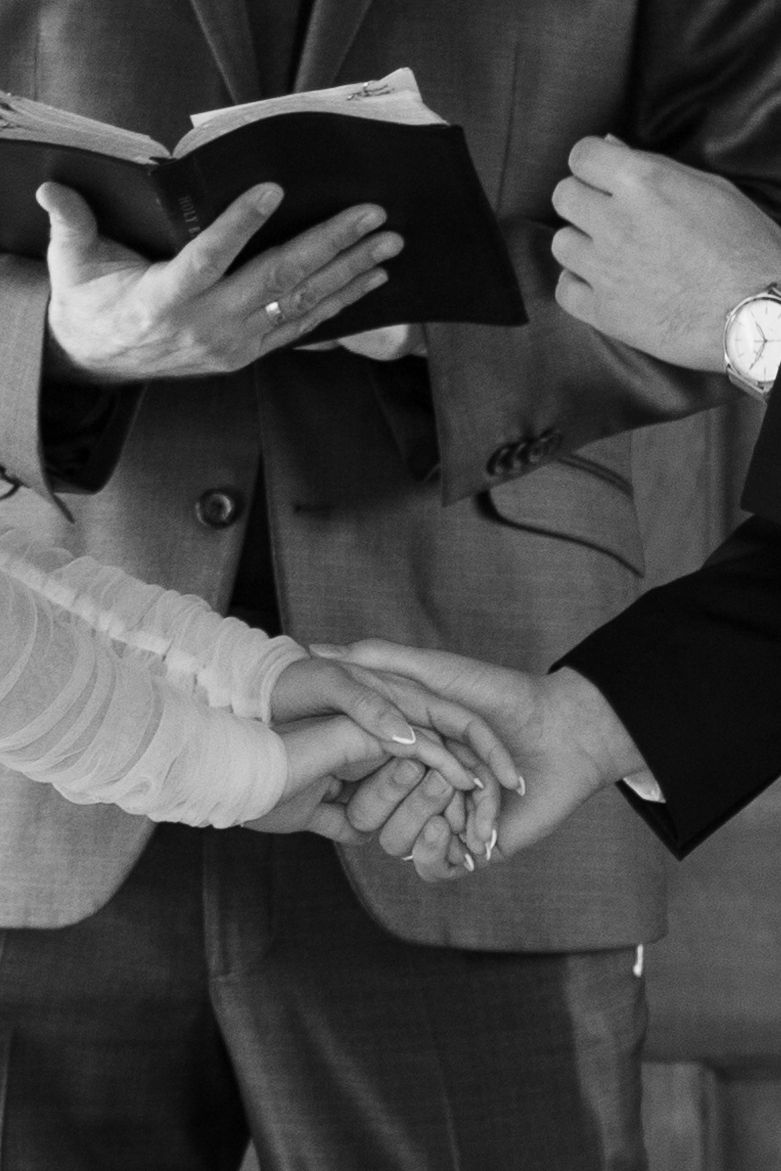 Black and white close-up of hands during an emotional wedding ceremony moment.