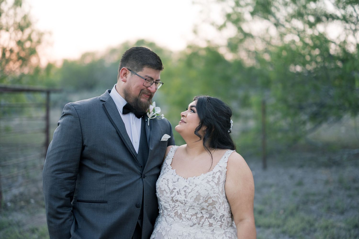 A tender moment between newlyweds captured in an outdoor setting at dusk.