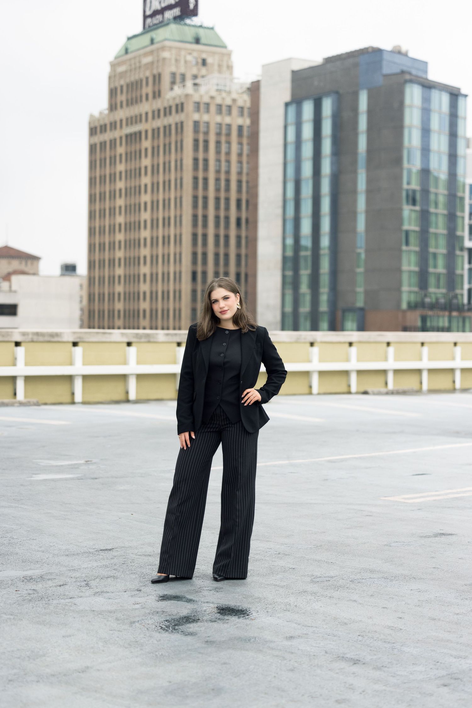 Professional photoshoot on a rooftop parking deck with city buildings in the background.