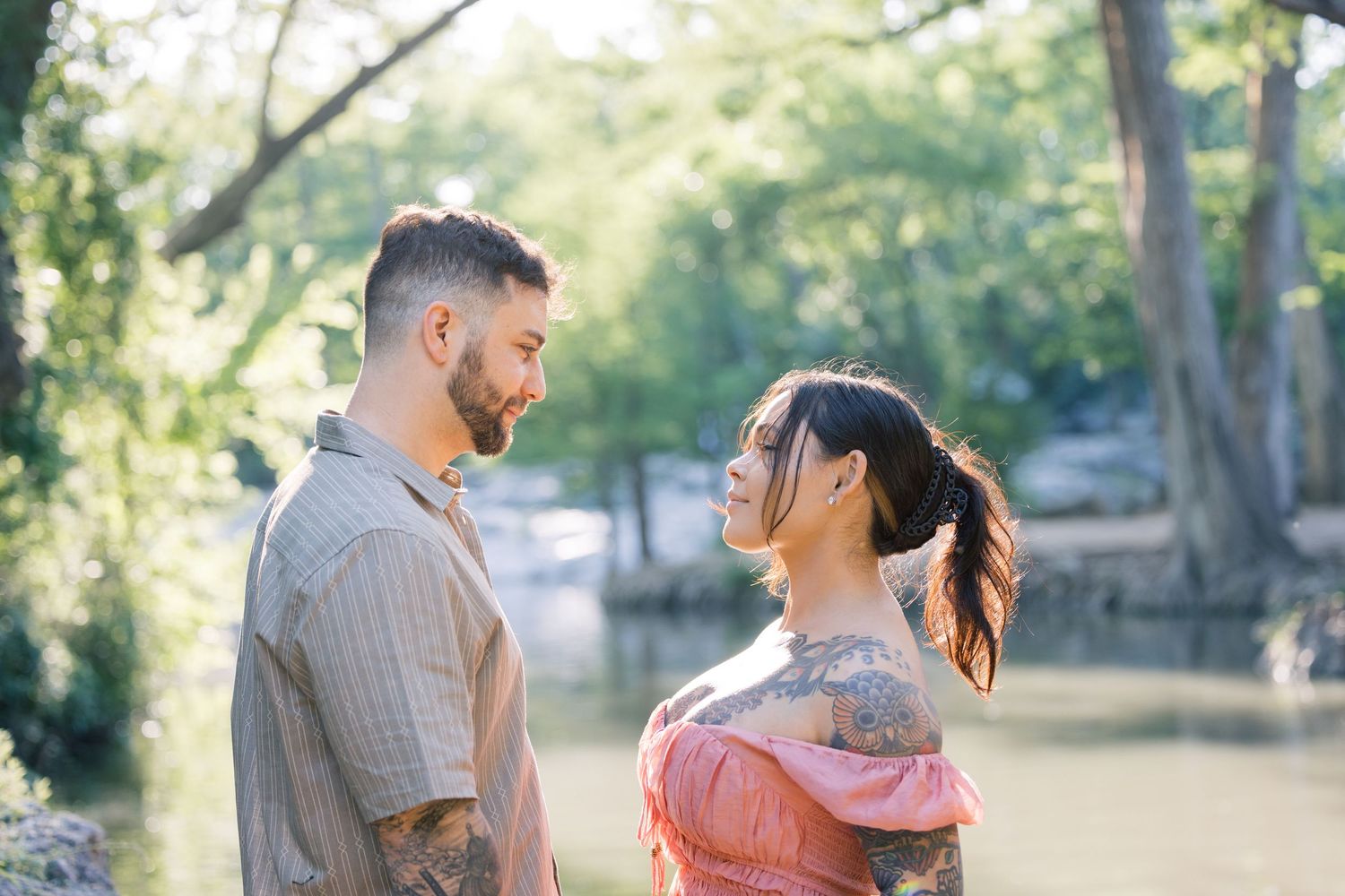 Candid moments captured of a couple in coral and beige outfits near a peaceful waterfront.