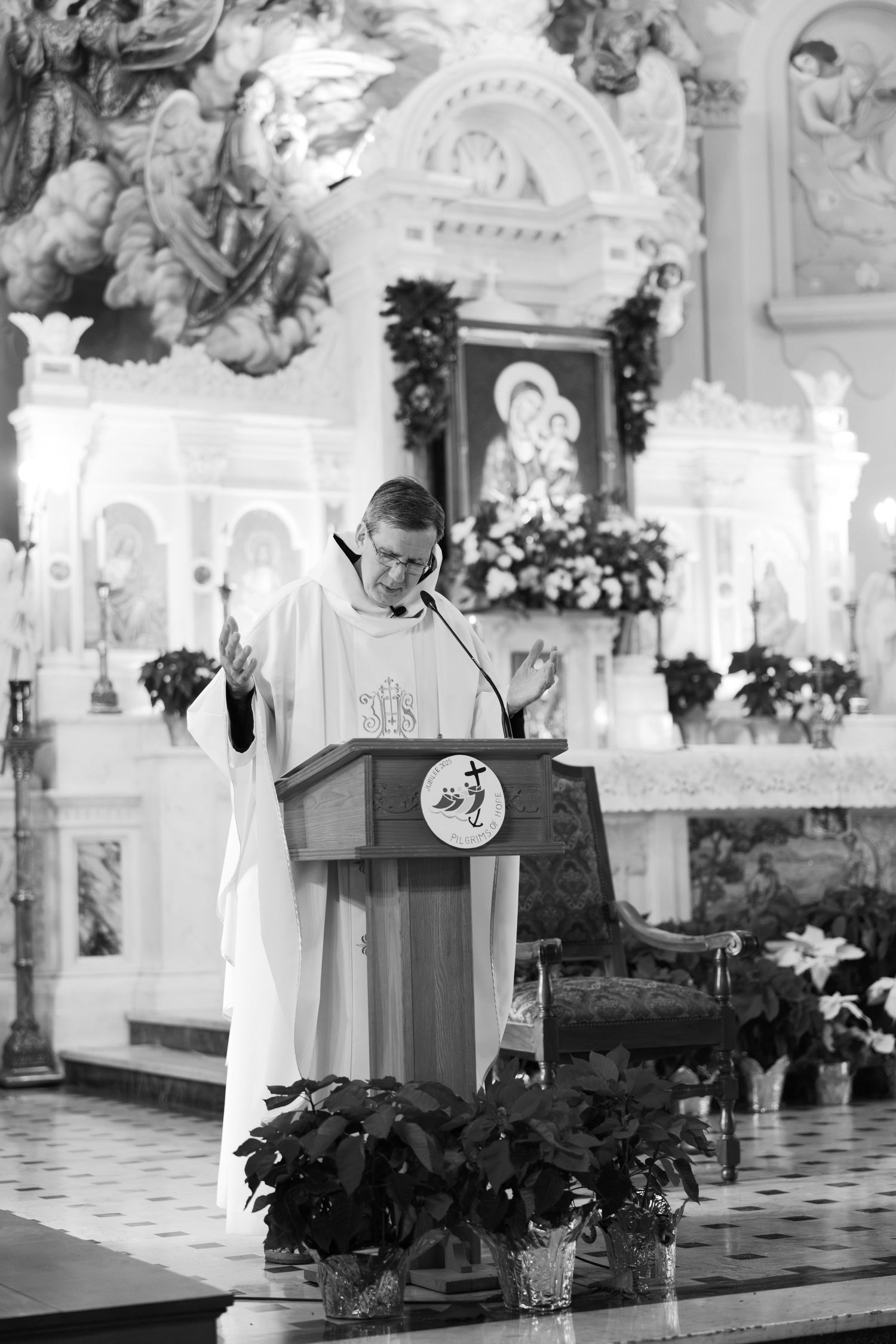 Priest delivering a sermon at an ornately decorated Catholic church altar during a wedding ceremony.