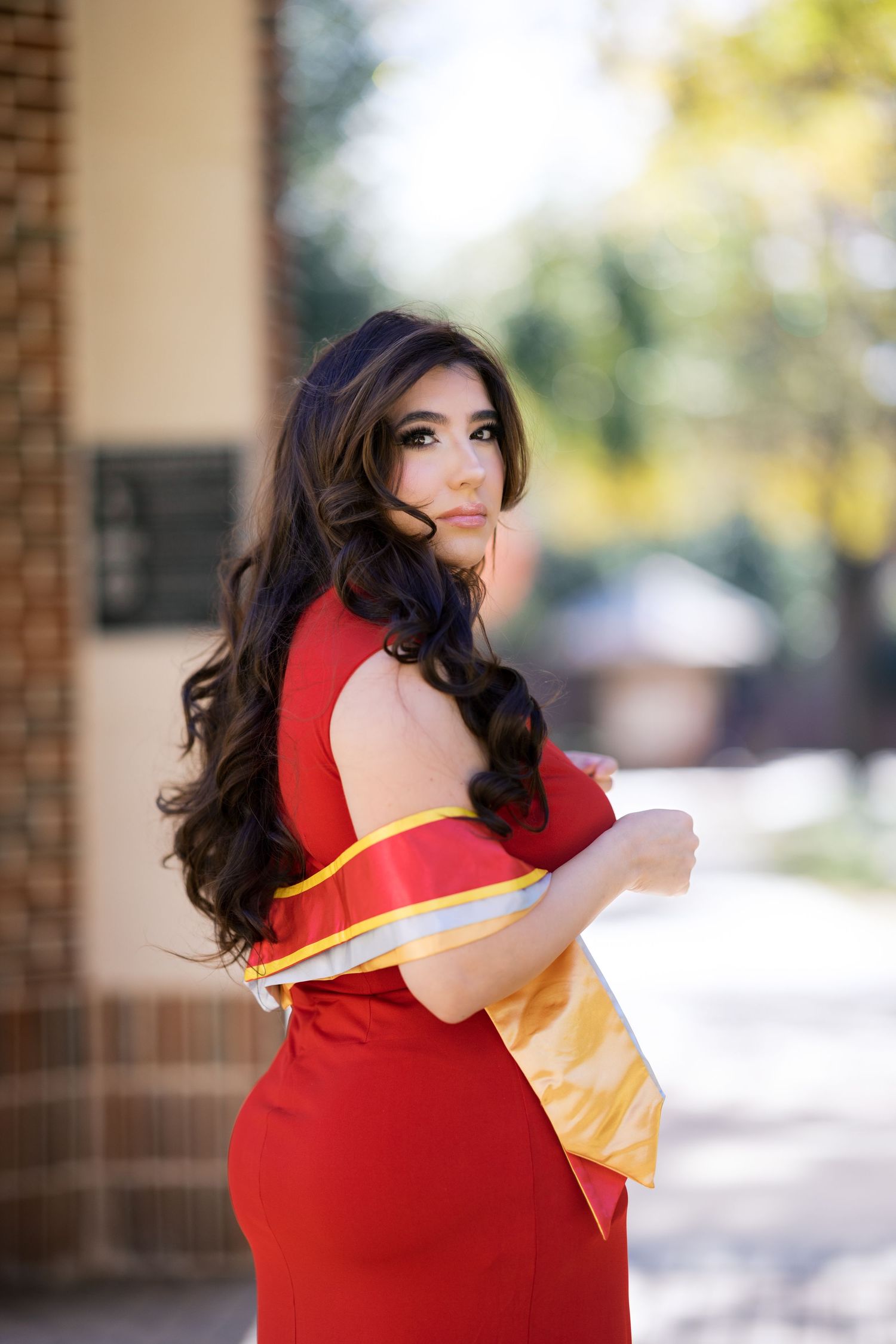 A flowing red dress with yellow accent creates an elegant silhouette.