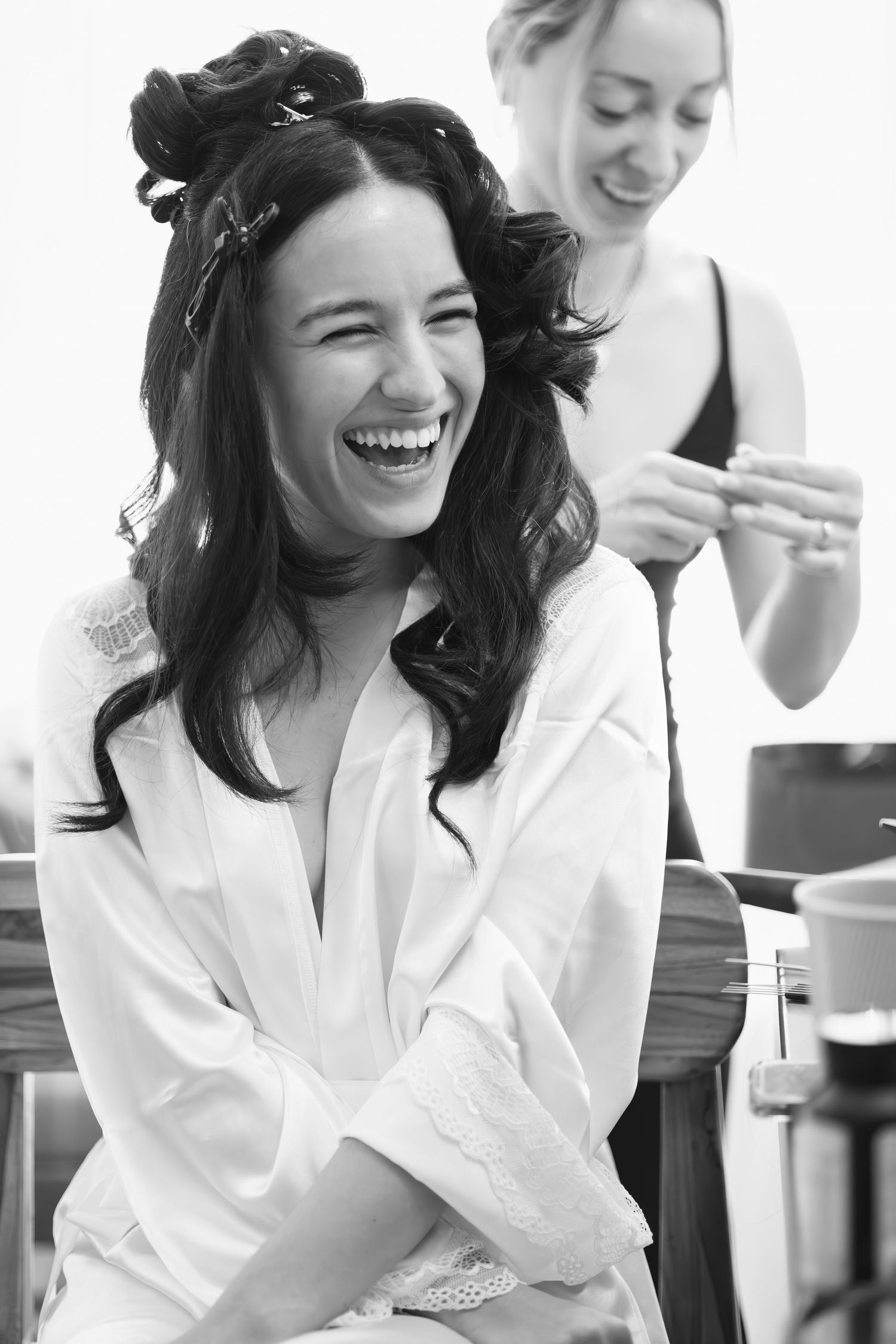 Black and white photo of joyful preparations in a white robe before the wedding ceremony.