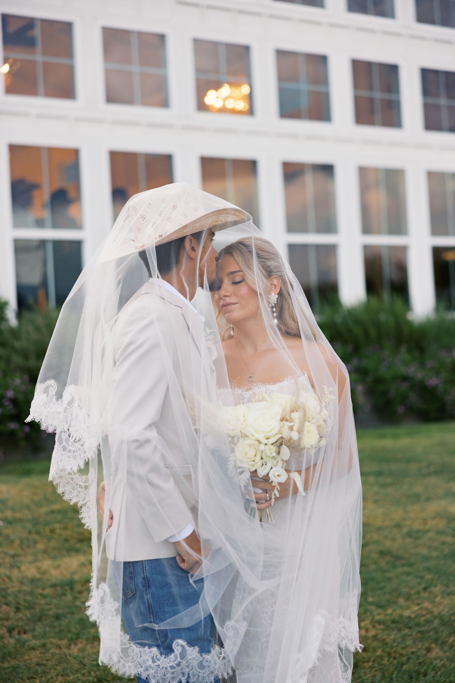 A series of romantic wedding photos showing a couple embracing under a flowing lace veil.